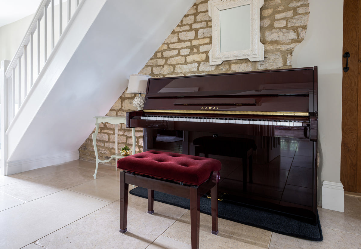 Toàn cảnh KAWAI K15E màu gỗ gụ Mahogany, chính diện trong phòng khách, nằm dưới gầm cầu thang