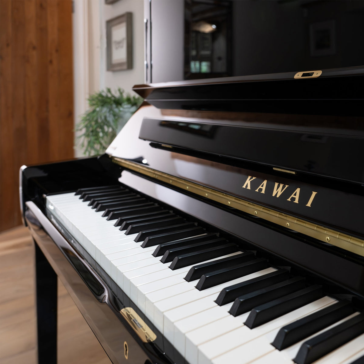 Chụp một góc đàn piano KAWAI K600 từ giữa bàn phím hất ra phía bên trái, cận cảnh logo hãng, bàn phím trắng đen đều tăm tắp