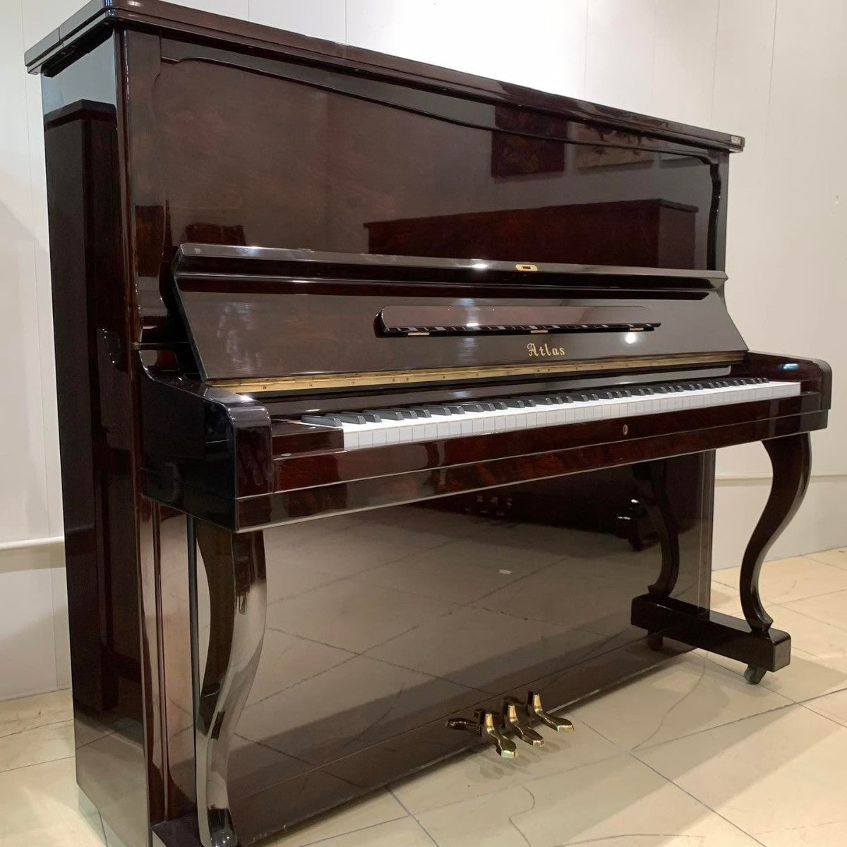 Đàn piano cơ upright TÂN NHẠC CỤ Atlas A55M màu đỏ rượu vang bóng sang trọng, thiết kế cổ điển với chân đàn uốn cong.