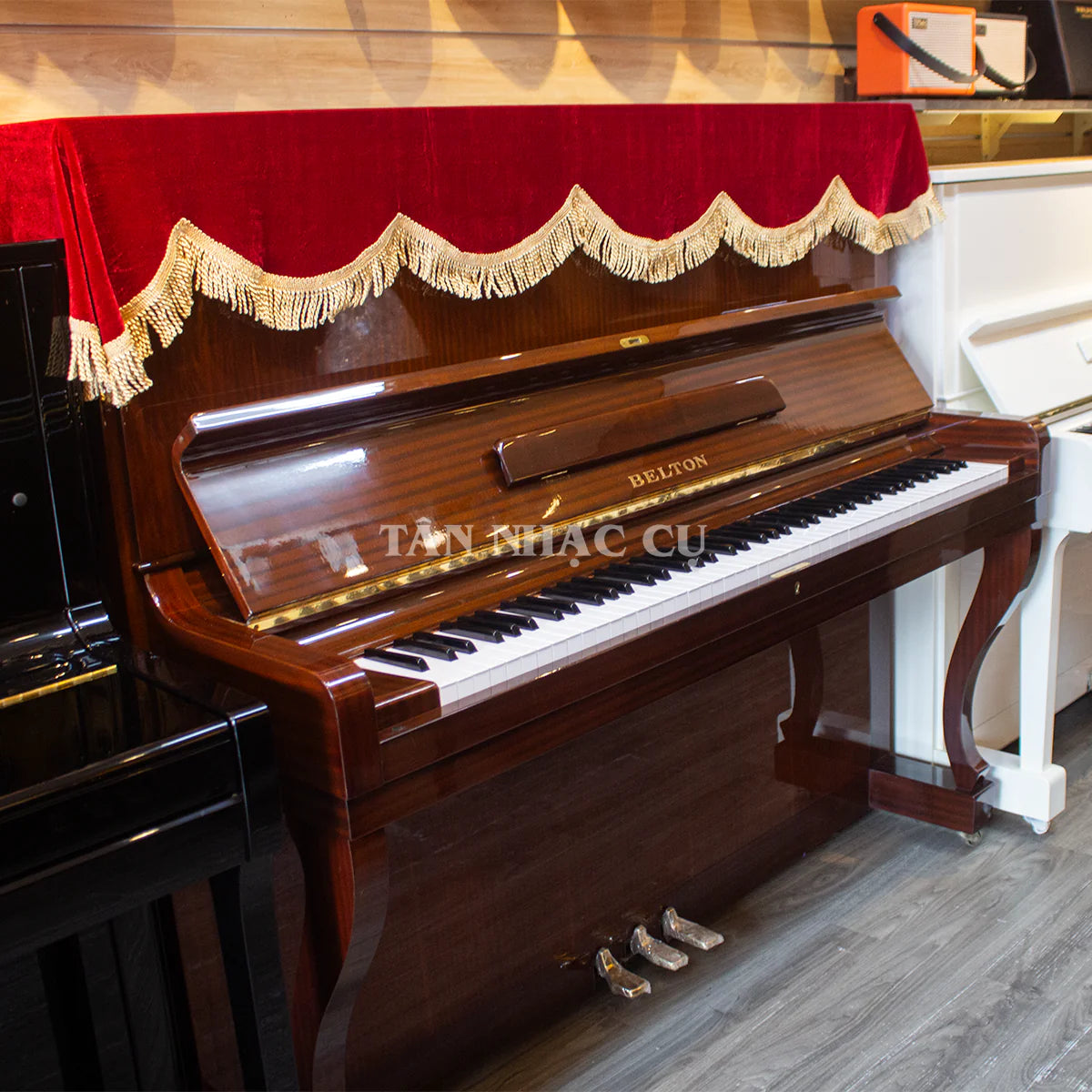 Đàn piano cơ TÂN NHẠC CỤ Belton FU50 màu gỗ nâu cổ điển với khăn phủ đỏ, thiết kế upright sang trọng
