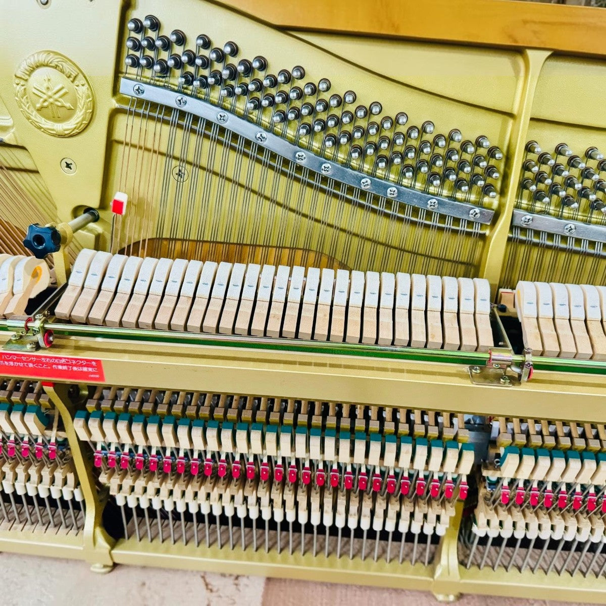 Bộ máy cơ bên trong đàn piano Yamaha HQ300SX tại TÂN NHẠC CỤ với khung gang vàng và các búa đàn chi tiết