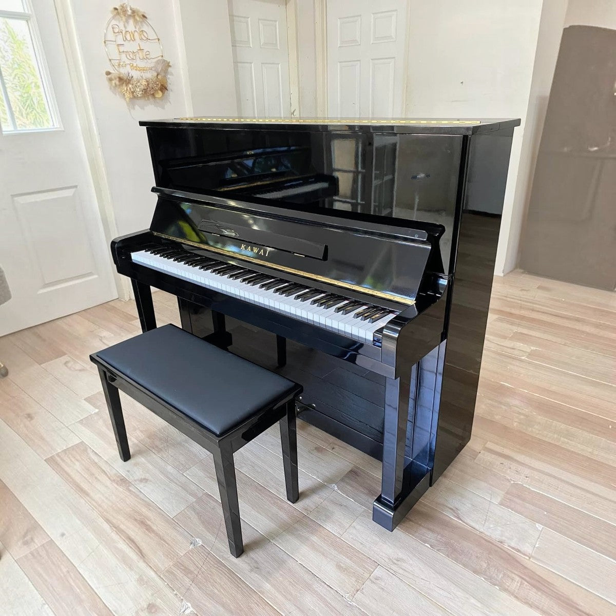 Đàn piano cơ Kawai KU1D màu đen bóng sang trọng tại TÂN NHẠC CỤ, thiết kế upright cổ điển với ghế đàn đi kèm.