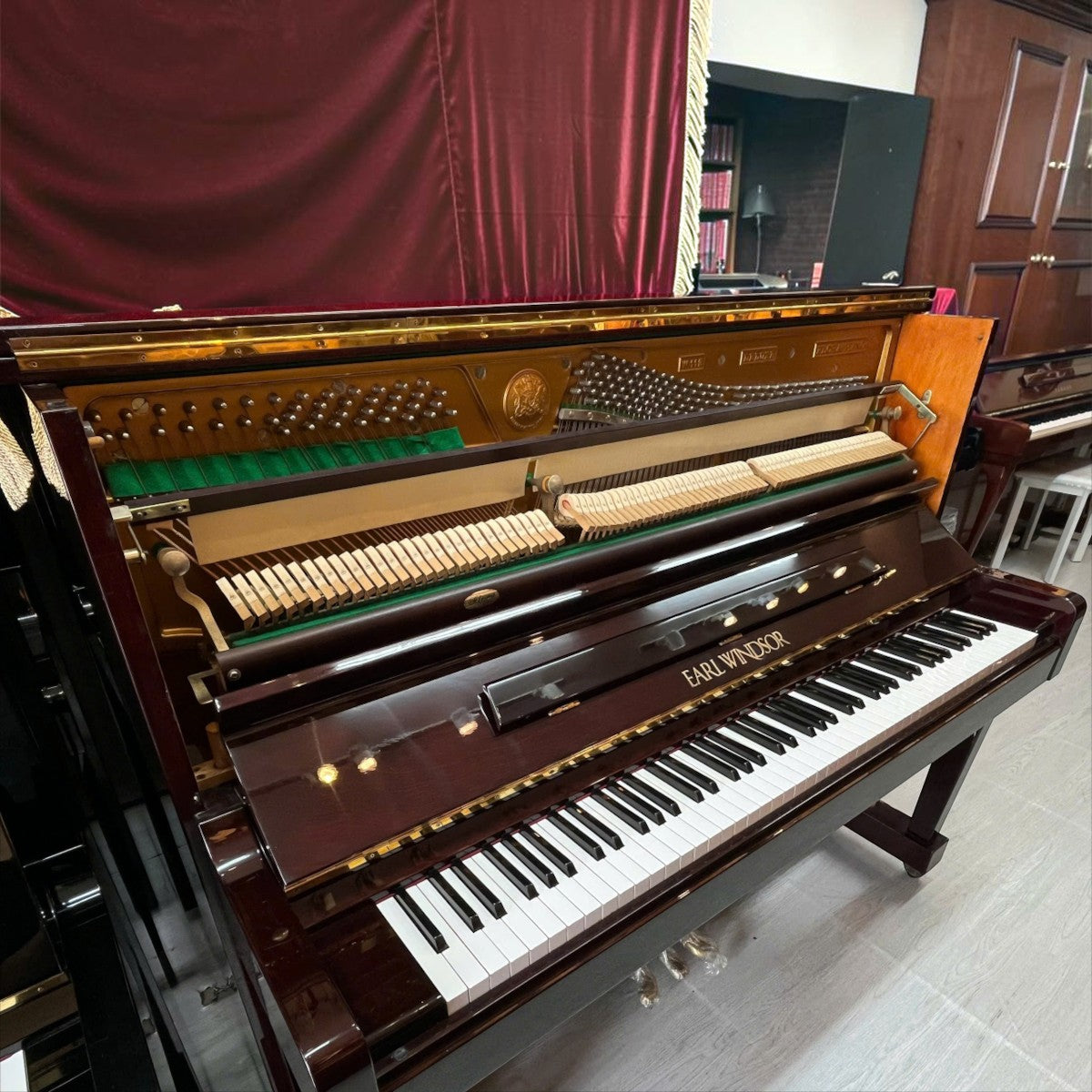 Đàn piano cơ upright TÂN NHẠC CỤ Earl Windsor màu nâu đỏ bóng với bộ máy bên trong lộ rõ, thiết kế sang trọng.