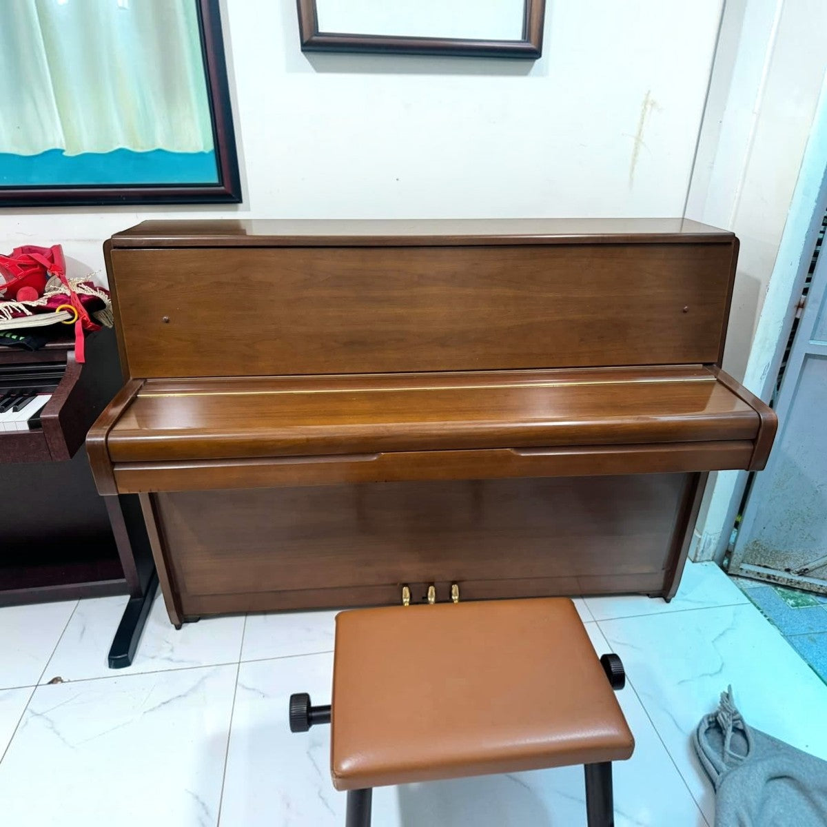 Đàn piano cơ Yamaha M1 màu gỗ tự nhiên thanh lịch tại TÂN NHẠC CỤ, thiết kế upright nhỏ gọn với ghế ngồi đồng bộ.