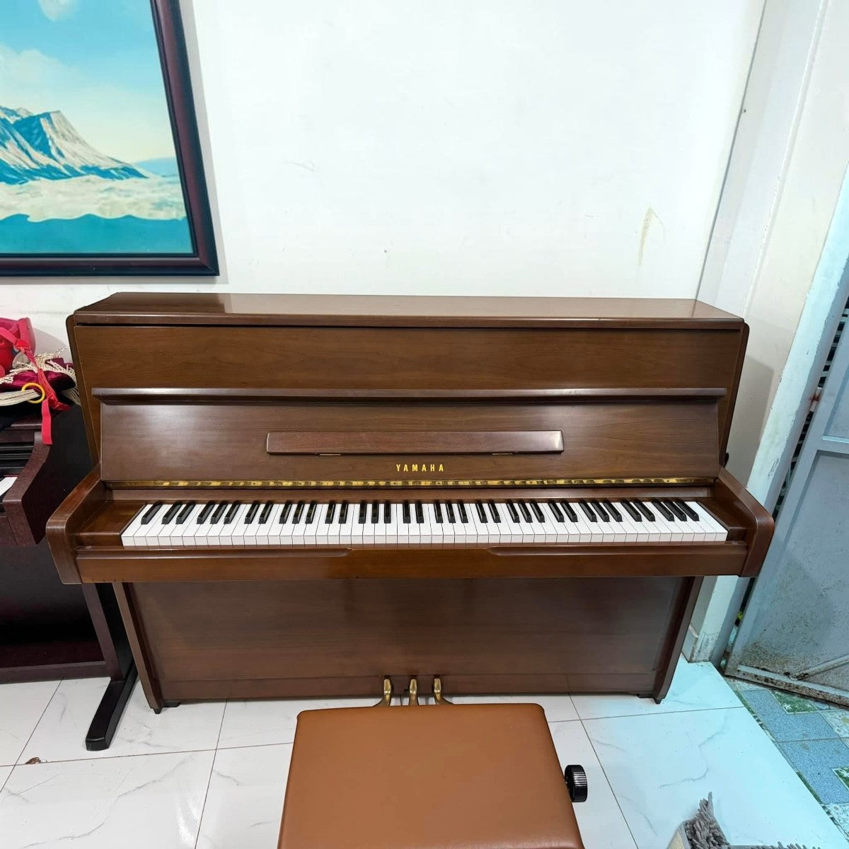 Đàn piano cơ Yamaha M1 màu gỗ nâu sang trọng, thiết kế upright nhỏ gọn, thanh thoát tại cửa hàng TÂN NHẠC CỤ.