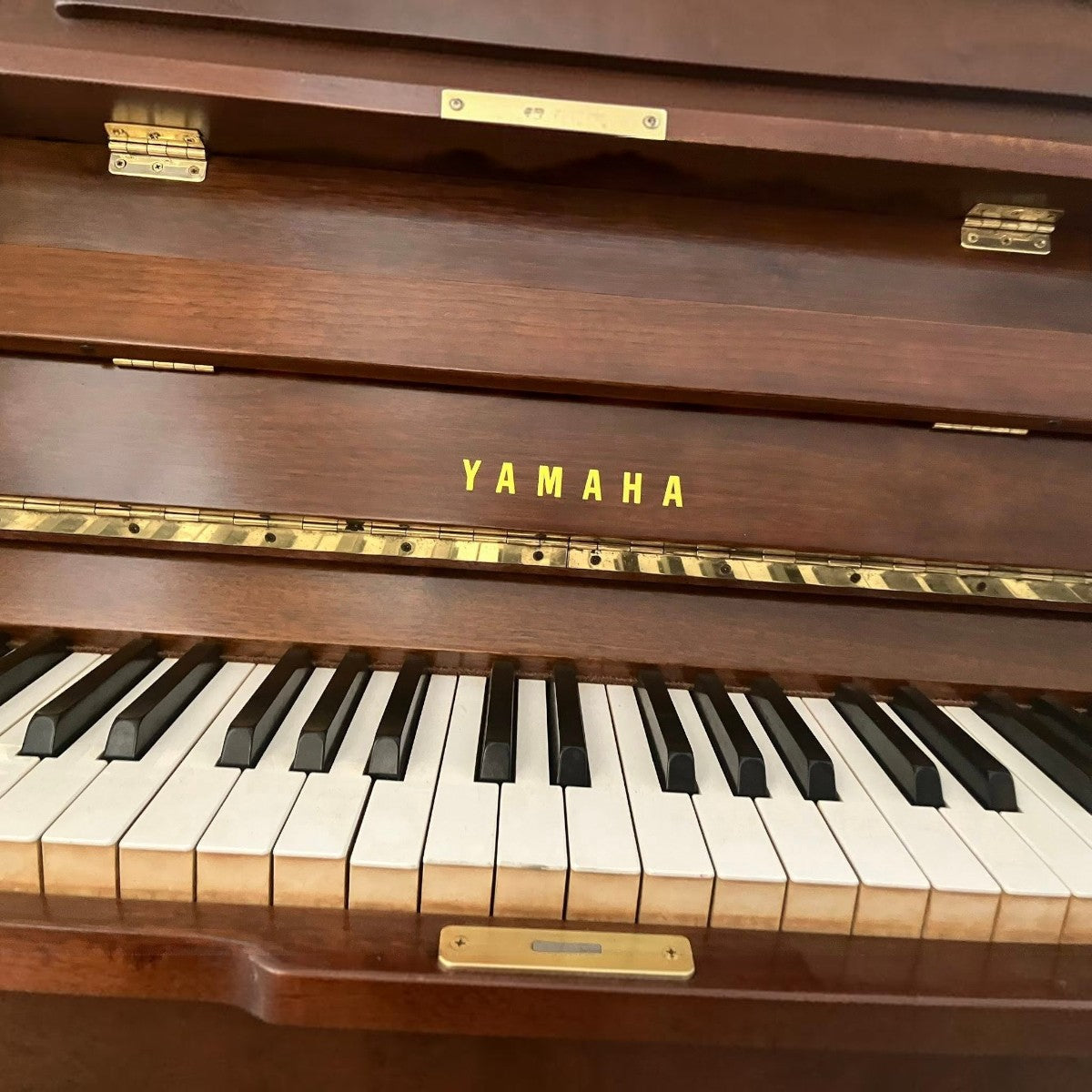 Đàn piano cơ Yamaha M1 màu gỗ nâu sang trọng với logo Yamaha nổi bật trên nắp đàn tại cửa hàng TÂN NHẠC CỤ