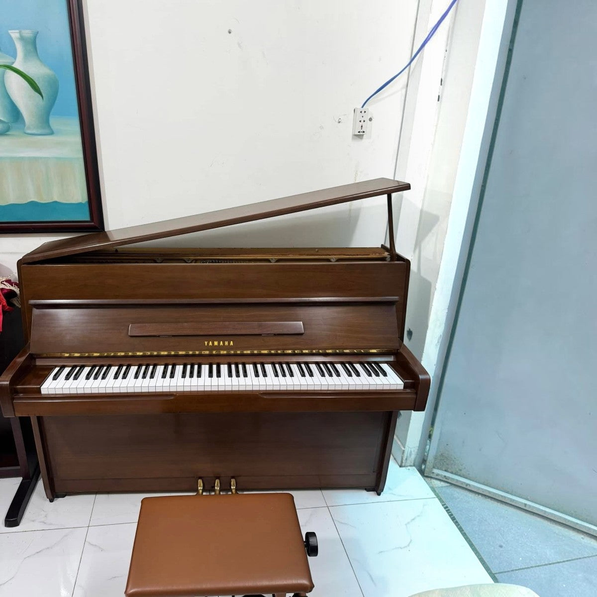 Đàn piano cơ Yamaha M1 màu gỗ nâu sang trọng tại Tân Nhạc Cụ với thiết kế upright nhỏ gọn và ghế đàn đồng bộ