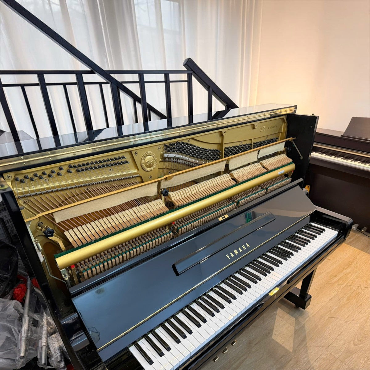 Đàn piano cơ Yamaha U3A màu đen bóng tại TÂN NHẠC CỤ với nắp trên mở lộ bộ máy và khung gang vàng đồng bên trong