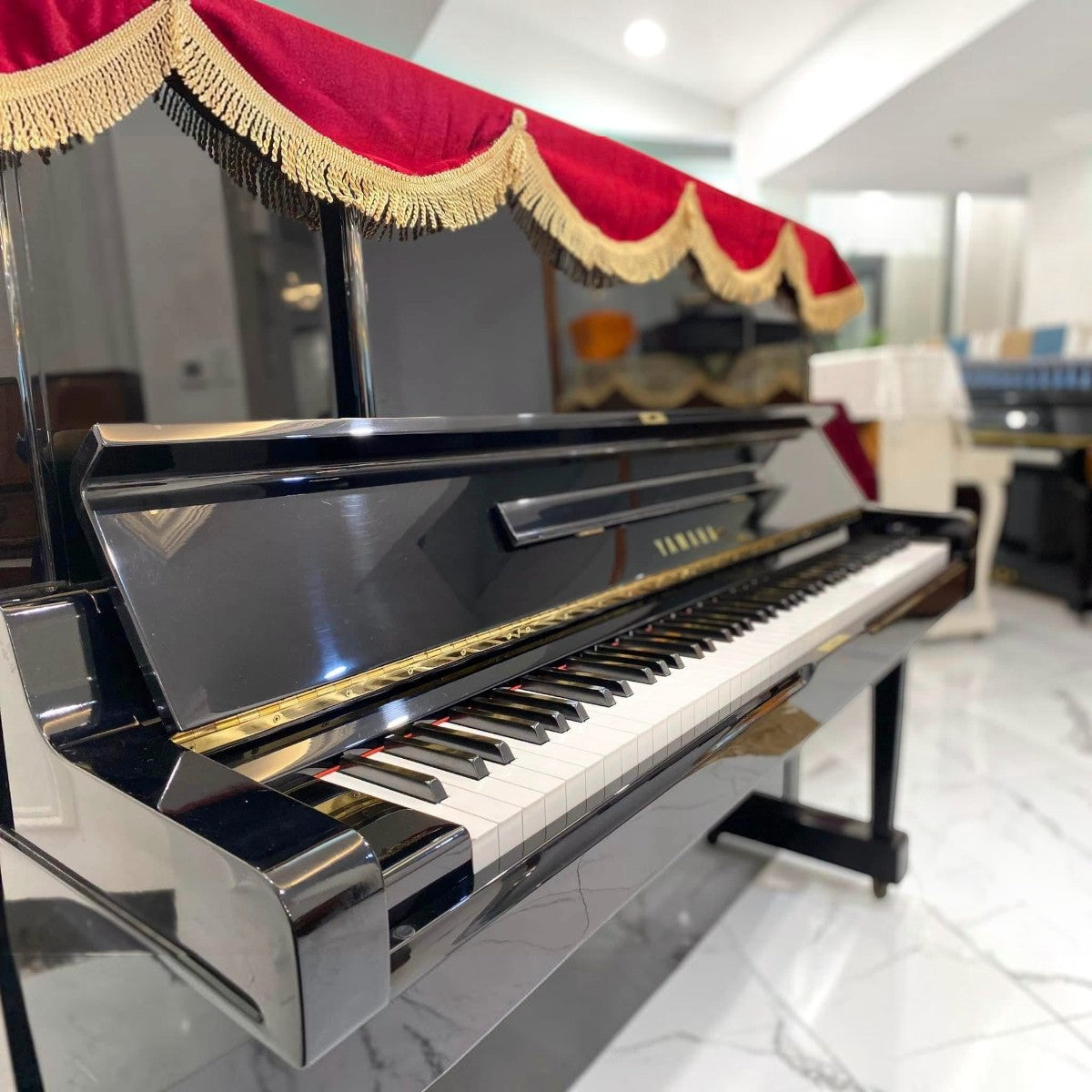 Đàn piano cơ Yamaha UX3 màu đen bóng sang trọng với khăn phủ đỏ tại cửa hàng TÂN NHẠC CỤ