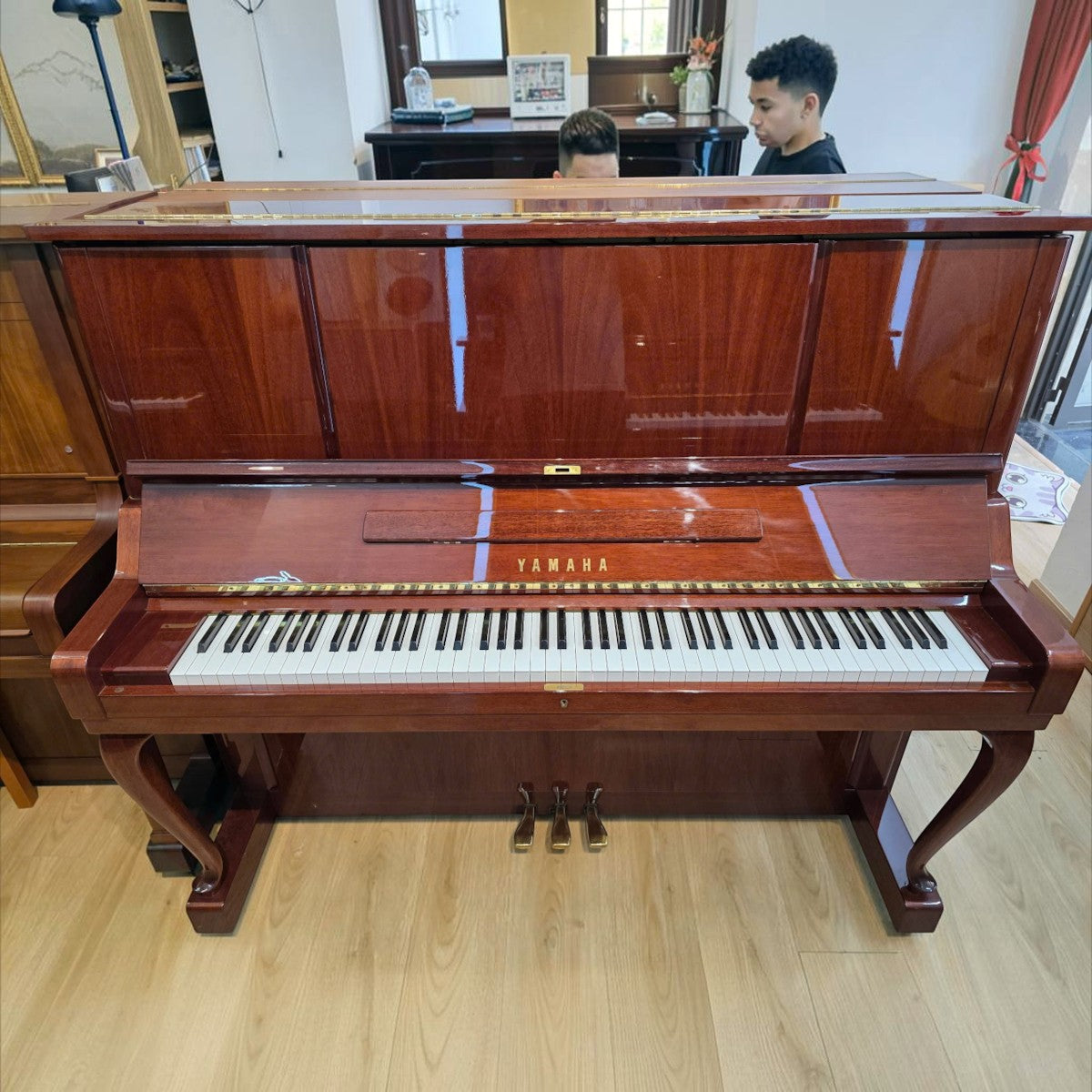 Đàn piano cơ Yamaha W106B cũ với mặt vân gỗ óc chó và gụ sang trọng, kiểu dáng cổ điển tại cửa hàng TÂN NHẠC CỤ