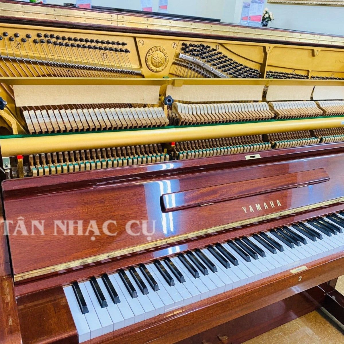 Đàn piano cơ Yamaha W106B tại TÂN NHẠC CỤ với mặt vân gỗ óc chó cổ điển, khung gang vàng và bộ máy bên trong chi tiết
