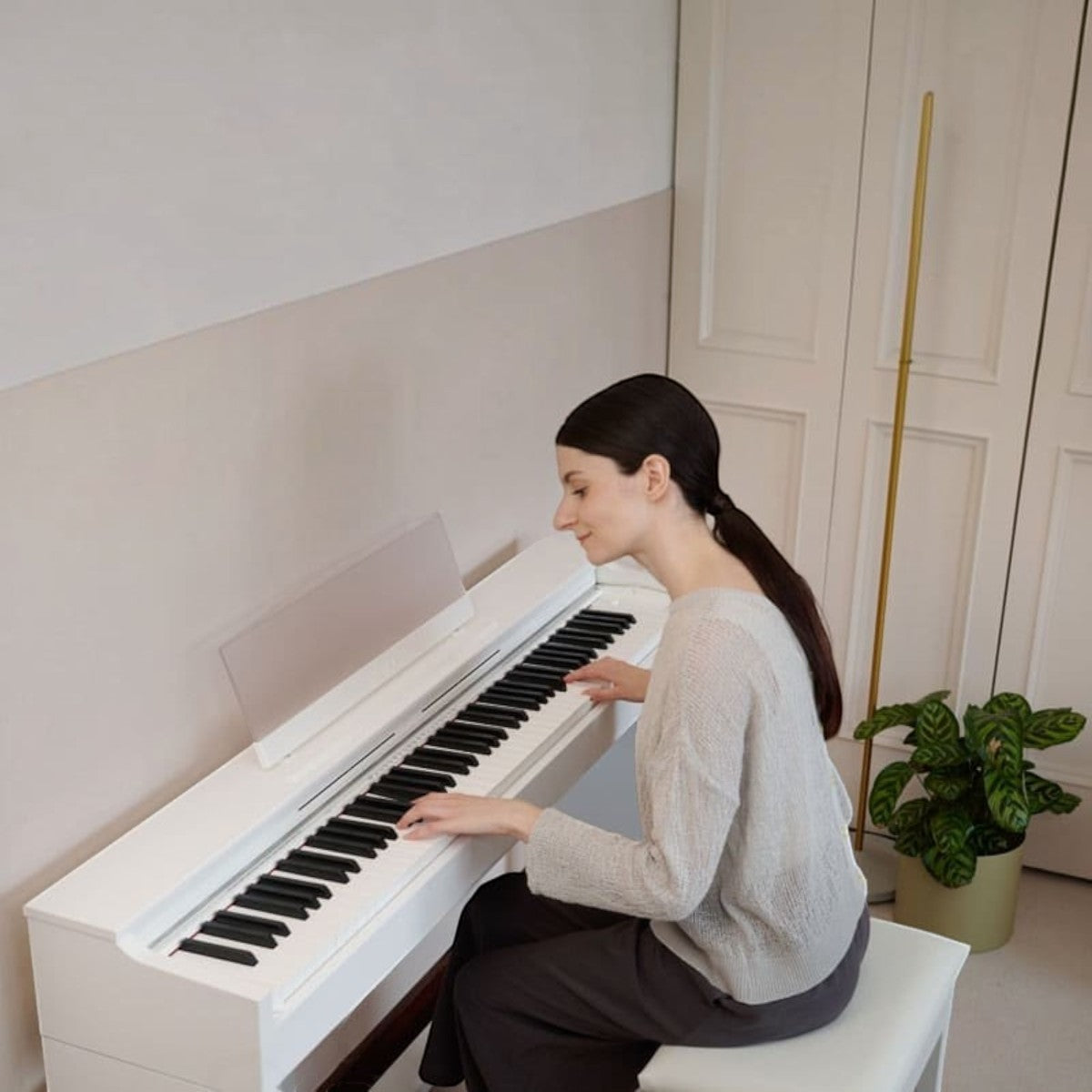 Người phụ nữ đang chơi đàn piano điện Casio AP-S200 màu trắng thanh lịch tại Tân Nhạc Cụ trong không gian phòng hiện đại
