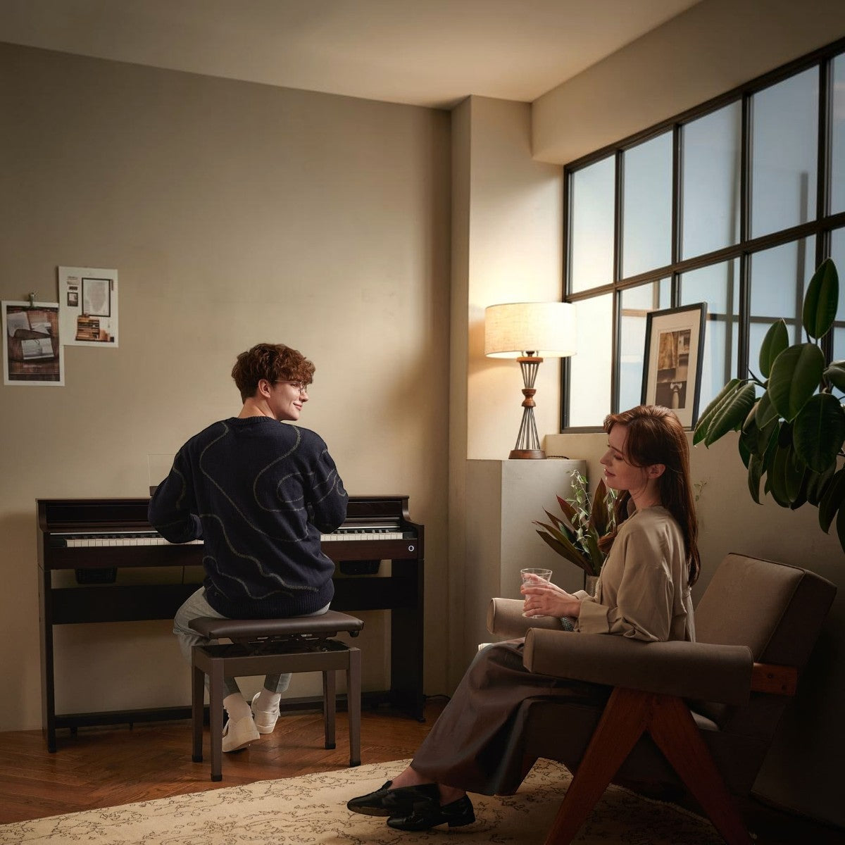 Nam thanh niên chơi đàn piano điện TÂN NHẠC CỤ Casio AP-S450 màu đen trong phòng khách hiện đại, có phụ nữ ngồi cạnh