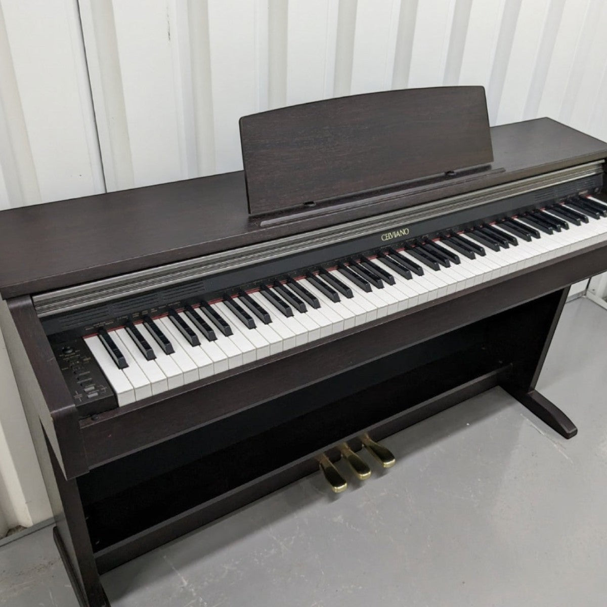 Đàn piano điện Casio AP200 dáng tủ màu nâu gỗ sang trọng tại TÂN NHẠC CỤ, bàn phím búa 88 phím và pedal kim loại.