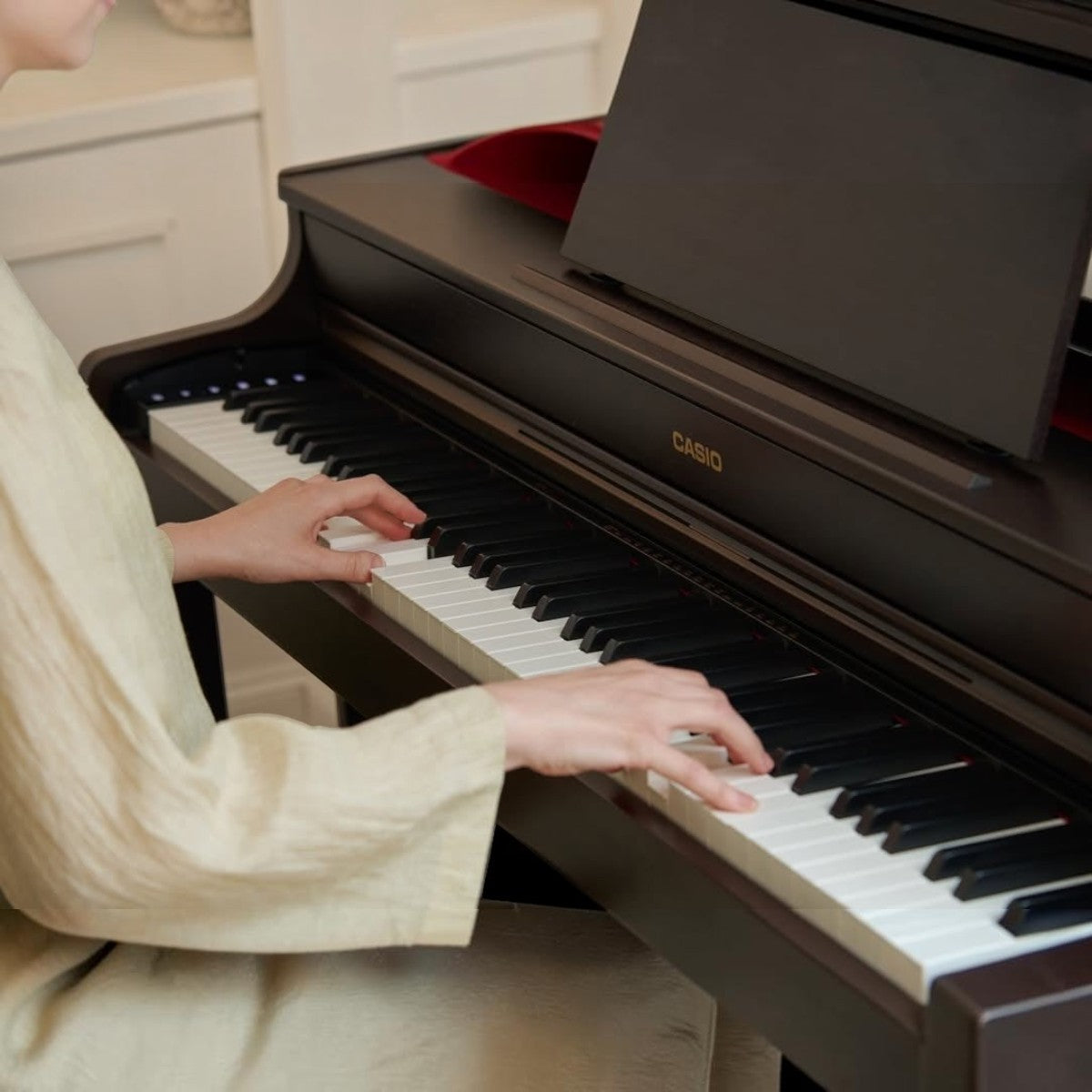 Người chơi đang tập đàn piano điện Casio AP-300 màu đen tại showroom Tân Nhạc Cụ với thiết kế dáng tủ sang trọng.