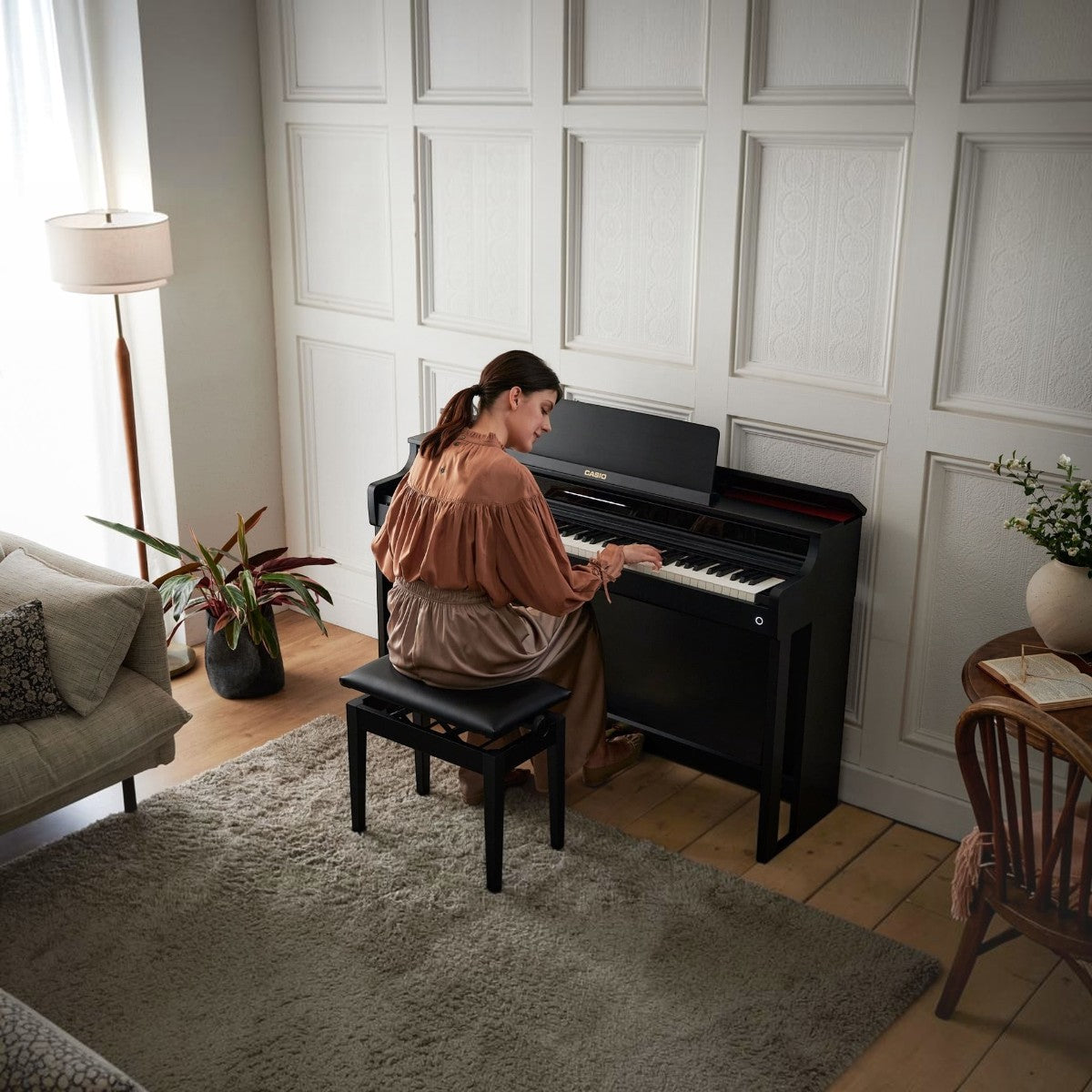 Người phụ nữ đang chơi đàn piano điện Casio AP-550 màu đen sang trọng tại Tân Nhạc Cụ, thiết kế dáng tủ hiện đại.