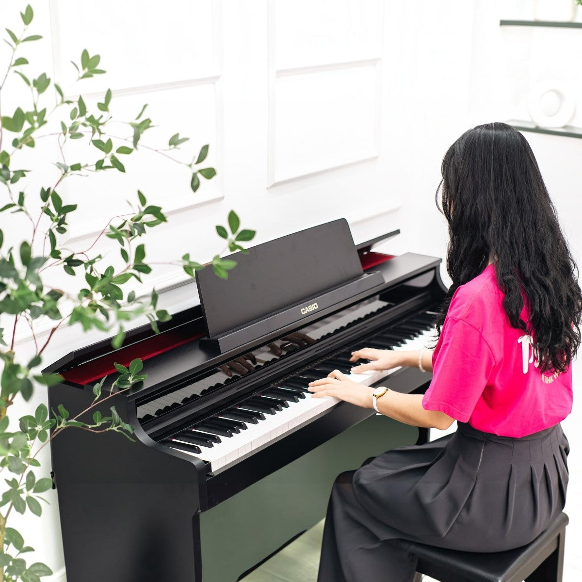 Cô gái chơi đàn piano điện Casio AP-550 màu đen tại showroom TÂN NHẠC CỤ với thiết kế dáng tủ sang trọng