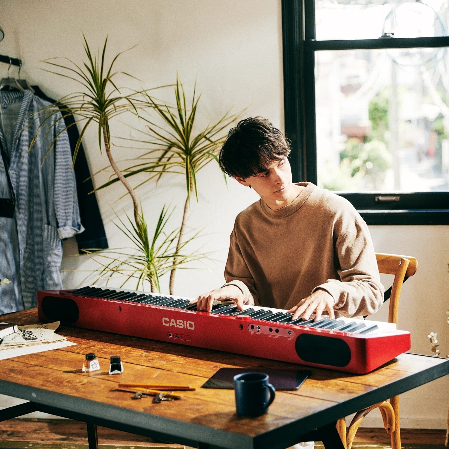 Nam thanh niên chơi đàn piano điện Casio PX-S1100 màu đỏ mỏng gọn trên bàn làm việc tại TÂN NHẠC CỤ