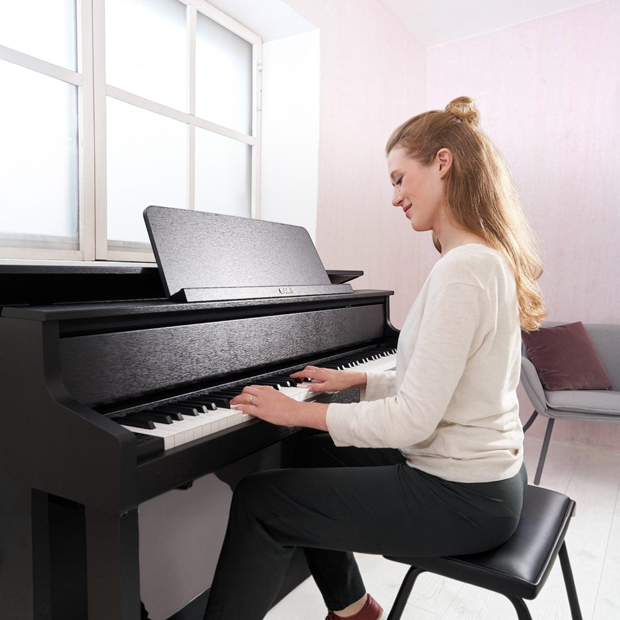 Người phụ nữ đang chơi đàn piano điện Casio GP-310 màu đen tại TÂN NHẠC CỤ, thiết kế sang trọng với phím gỗ búa cơ.