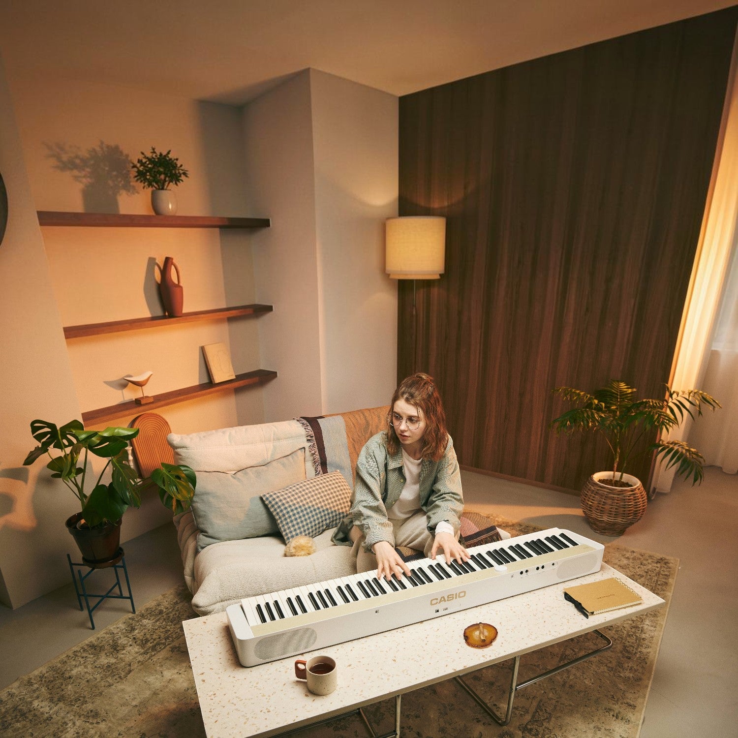 Người chơi đàn piano điện Casio PX-S1100 màu trắng tại phòng khách ấm cúng, sản phẩm chính hãng từ TÂN NHẠC CỤ