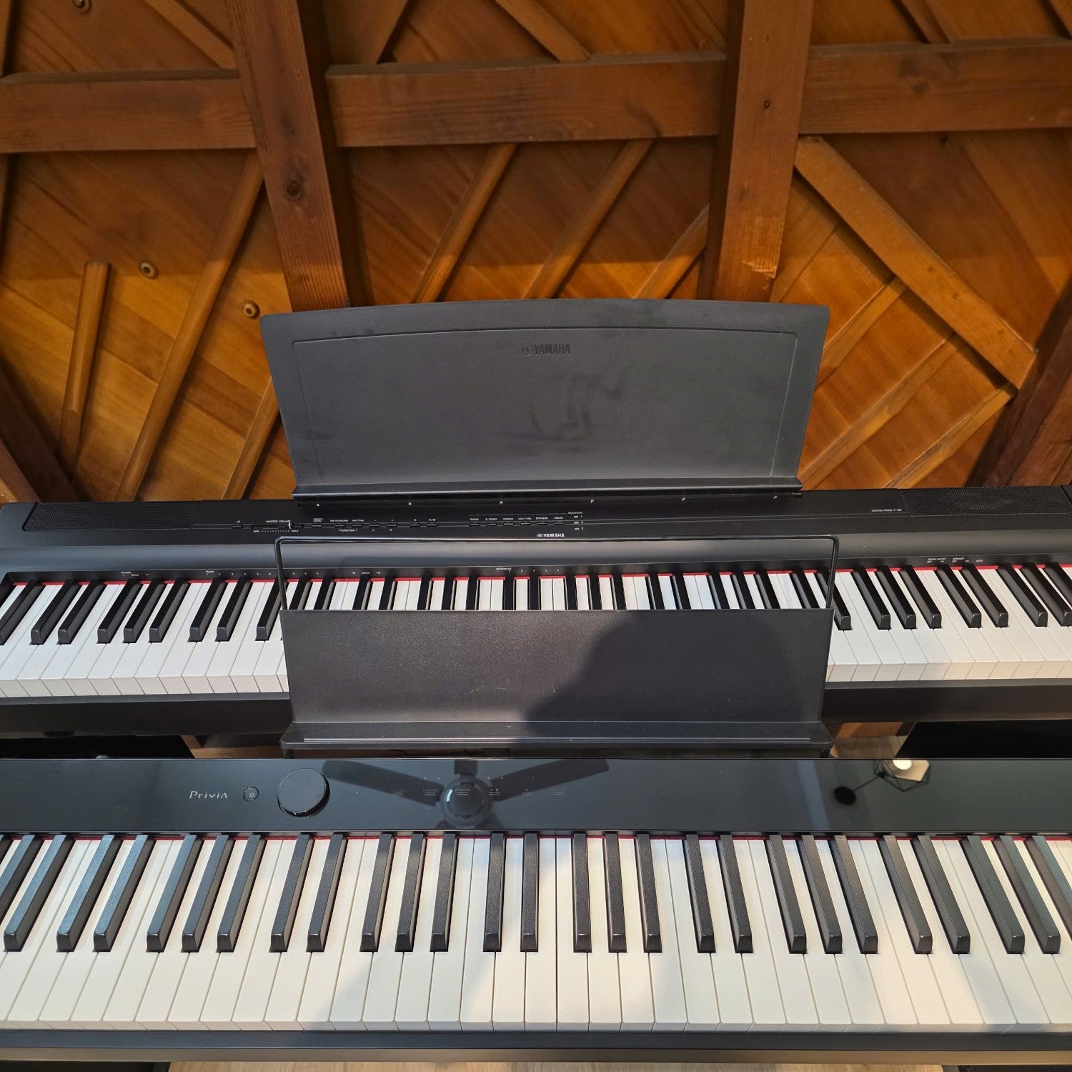 Đàn piano điện Casio PX-S1100 màu đen mỏng tại TÂN NHẠC CỤ, đặt phía trước một cây đàn piano khác