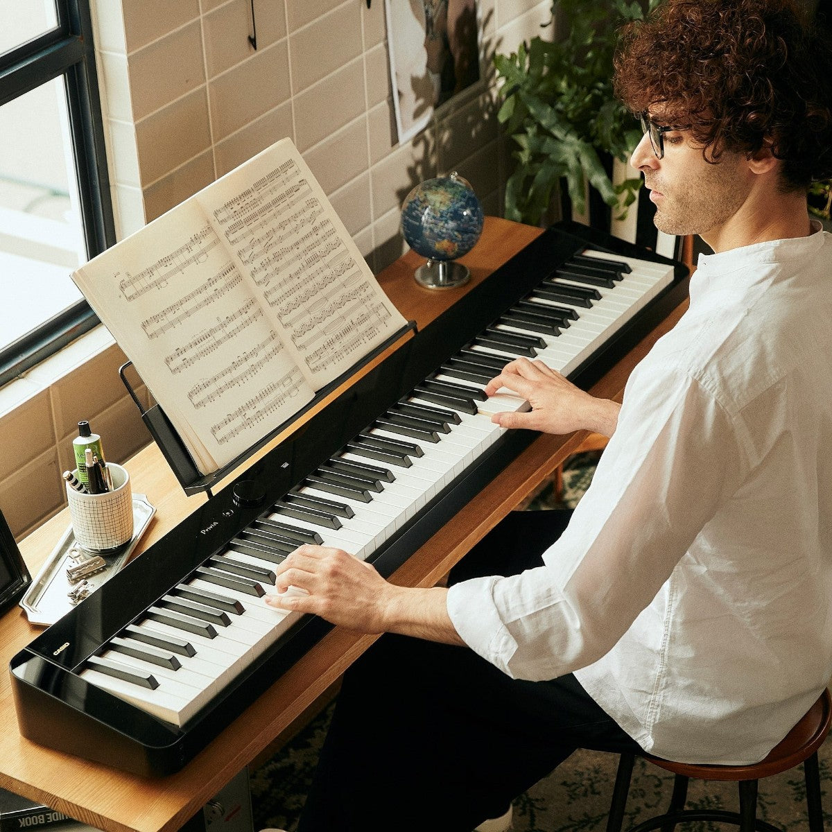Nam nghệ sĩ chơi đàn piano điện Casio PX-S5000 màu đen tại Tân Nhạc Cụ, nổi bật với phím gỗ-nhựa composite cao cấp.