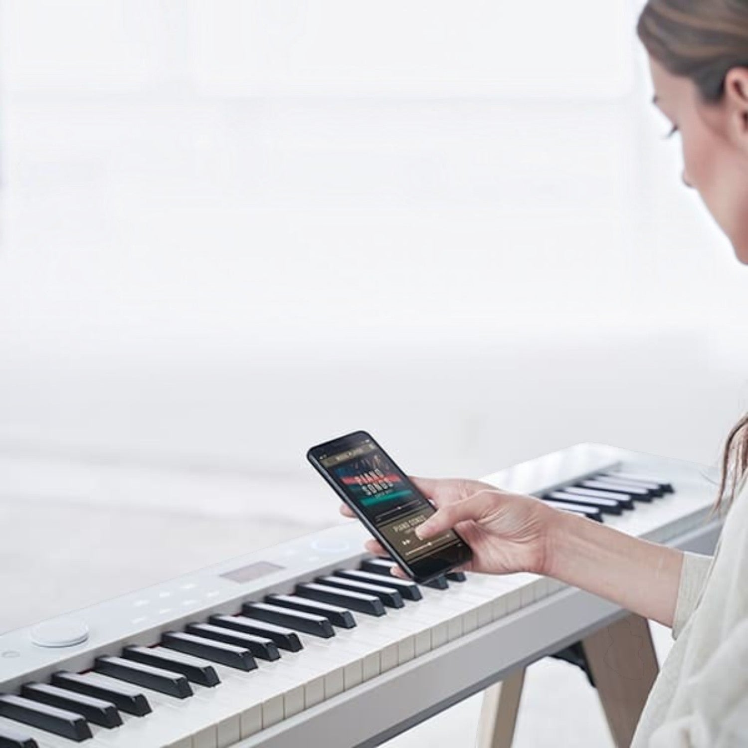 Người dùng kết nối điện thoại thông minh với đàn piano điện TÂN NHẠC CỤ Casio PX-S7000 màu trắng hiện đại