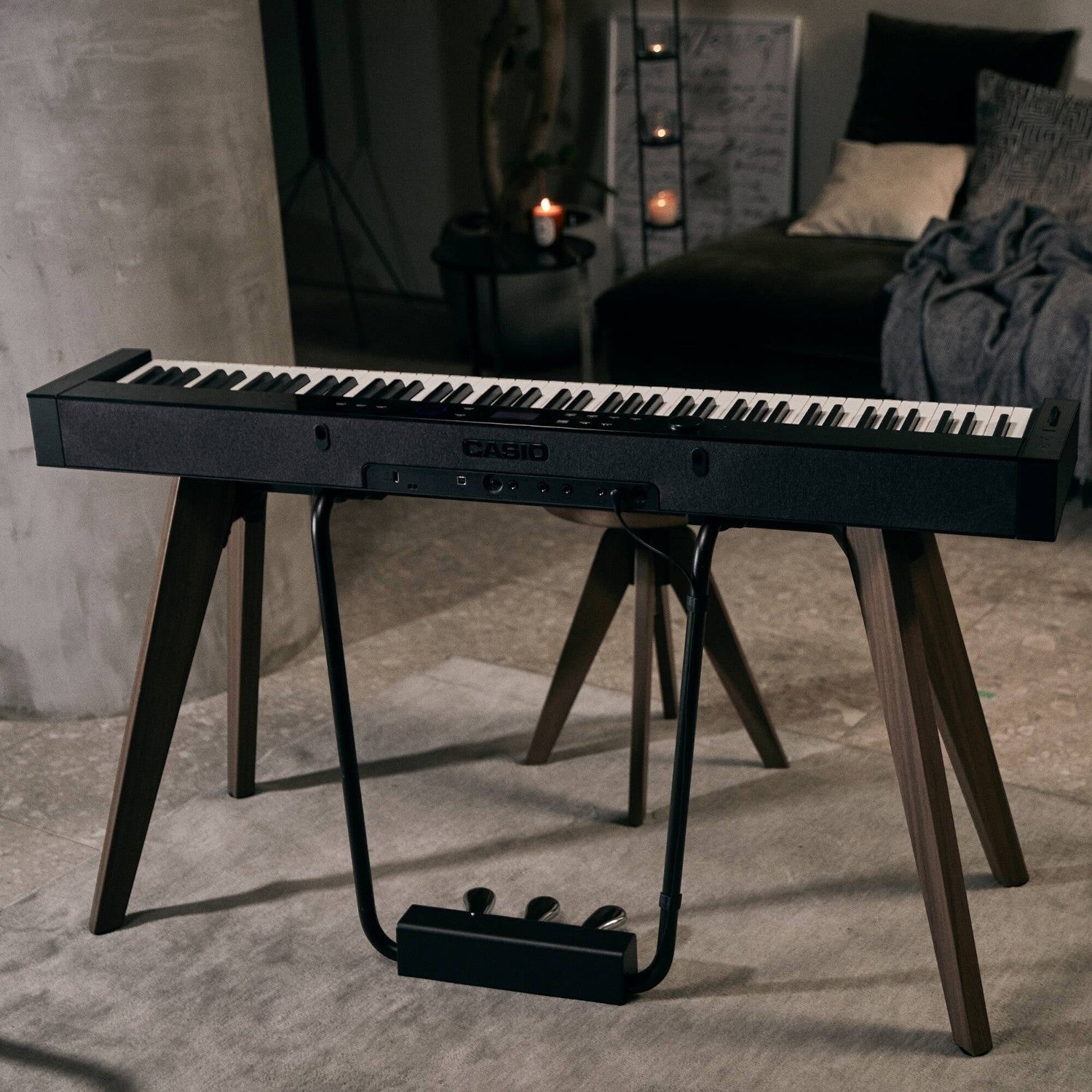 Đàn piano điện TÂN NHẠC CỤ Casio PX-S7000 màu đen với chân đế gỗ và bộ 3 bàn đạp cố định trong không gian nội thất