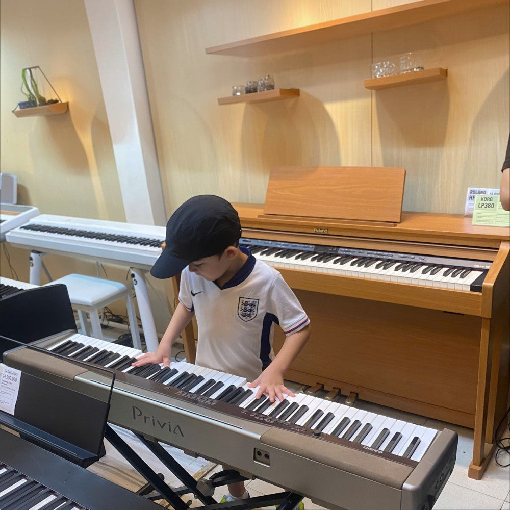 Bé trai đang chơi đàn piano điện Casio PX100 tại showroom TÂN NHẠC CỤ với thiết kế phím búa 88 phím nhỏ gọn