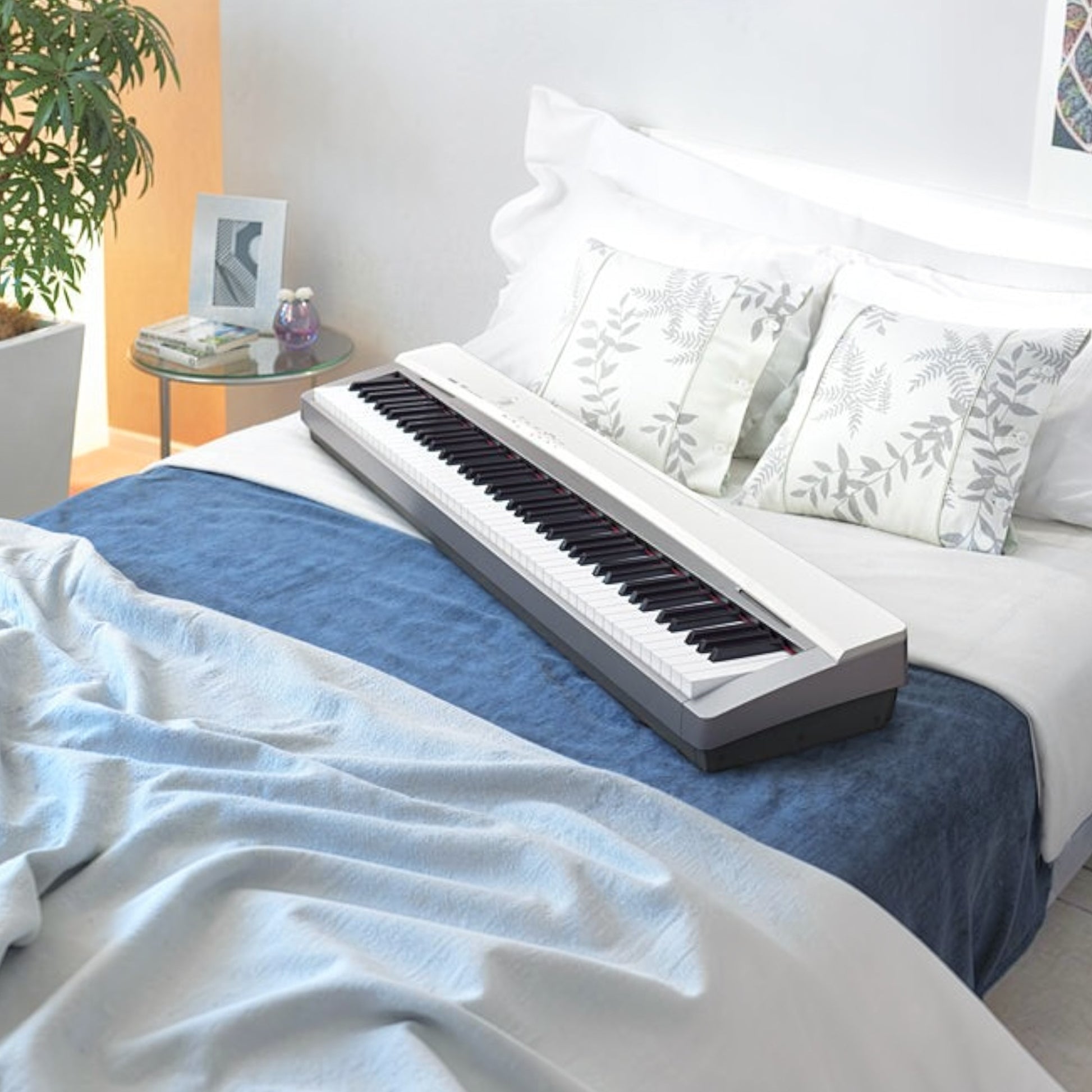 Đàn piano điện Casio PX130 màu trắng thiết kế gọn nhẹ đặt trên giường tại TÂN NHẠC CỤ