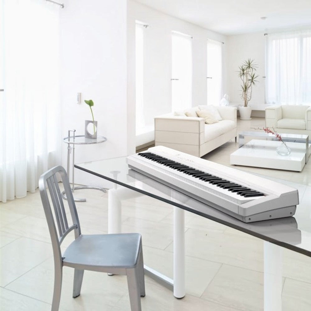 Đàn piano điện Casio PX135 màu trắng thiết kế gọn nhẹ, đặt trên bàn kính trong không gian phòng khách tại TÂN NHẠC CỤ