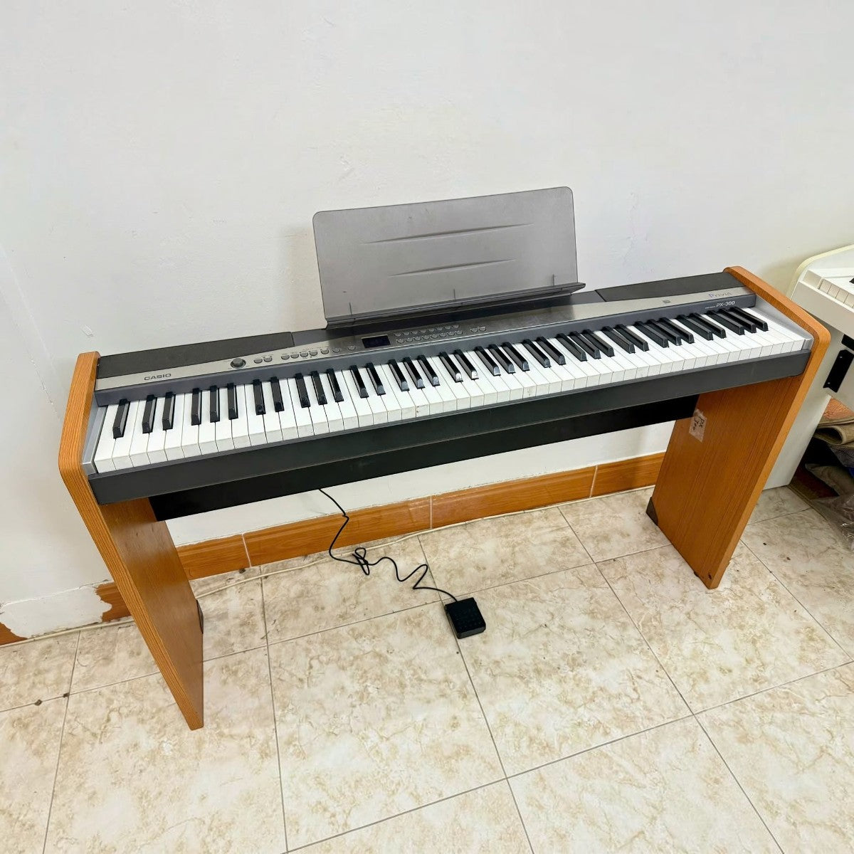 Đàn piano điện Casio PX300 tại TÂN NHẠC CỤ với thiết kế 88 phím búa, màu đen phối gỗ, kèm giá nhạc và pedal