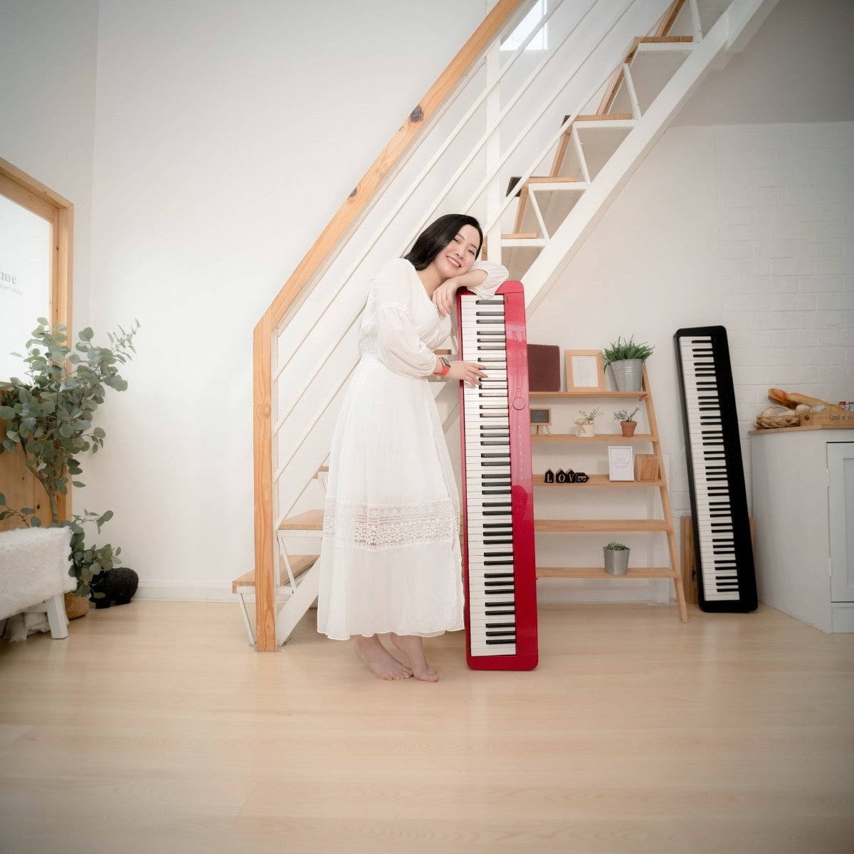 Cô gái mặc váy trắng tựa vào đàn piano điện Casio PX-S1000 màu đỏ tại TÂN NHẠC CỤ