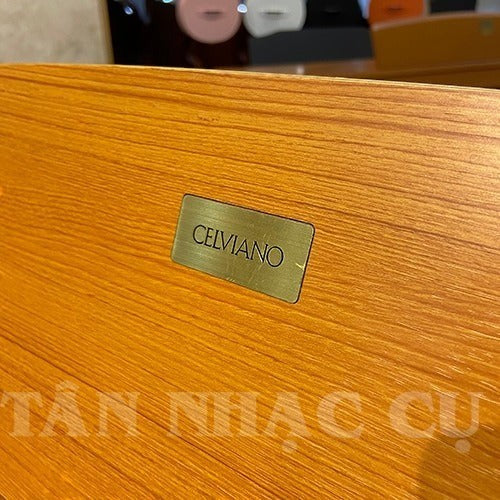 Logo Celviano bằng kim loại trên bề mặt gỗ vân sáng của đàn piano điện TÂN NHẠC CỤ