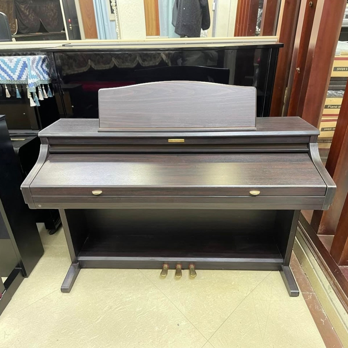Đàn piano điện Kawai CA71 màu gỗ tối tại cửa hàng TÂN NHẠC CỤ với thiết kế dáng tủ sang trọng và bàn phím gỗ.