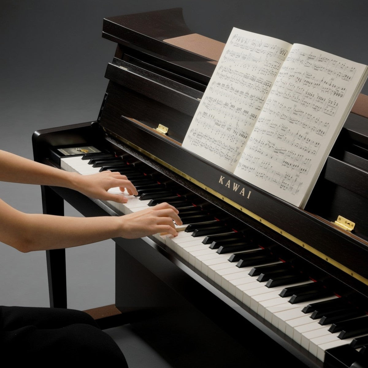 Người chơi đang sử dụng đàn piano điện Kawai CA99 màu đen bóng với bàn phím gỗ thật tại cửa hàng TÂN NHẠC CỤ