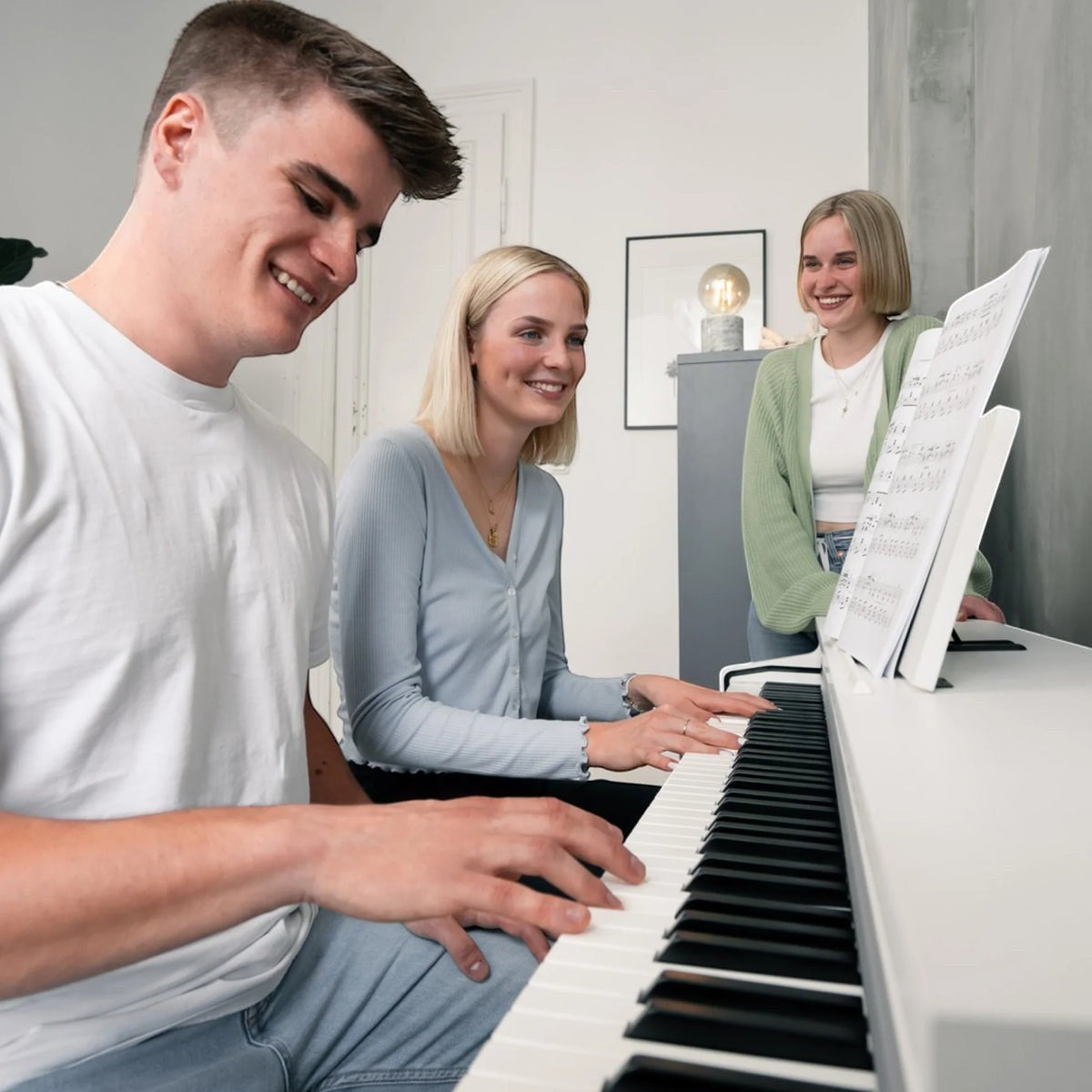 Ba người trẻ vui vẻ bên đàn piano điện Kawai CN201 màu trắng tại Tân Nhạc Cụ