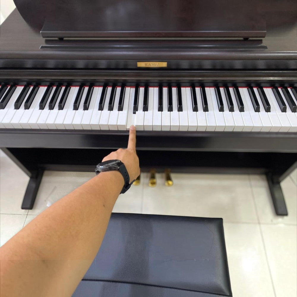Người chơi đang thử phím đàn piano điện Kawai CN22 dáng tủ màu nâu tại cửa hàng TÂN NHẠC CỤ