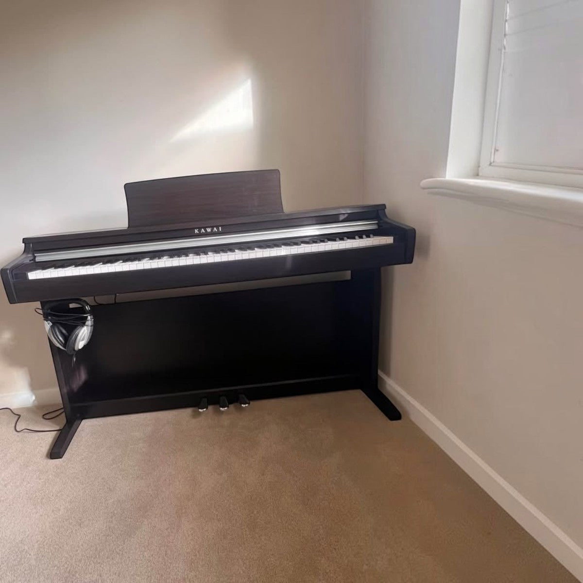 Đàn piano điện Kawai CX202 dáng tủ màu nâu gỗ sang trọng tại Tân Nhạc Cụ với 3 pedal và bàn phím búa cơ