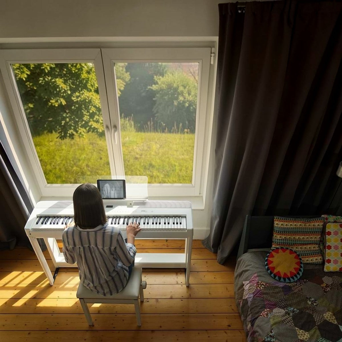 Người chơi đàn piano điện Kawai ES520 màu trắng tại Tân Nhạc Cụ, đặt cạnh cửa sổ trong phòng ngủ ấm cúng.