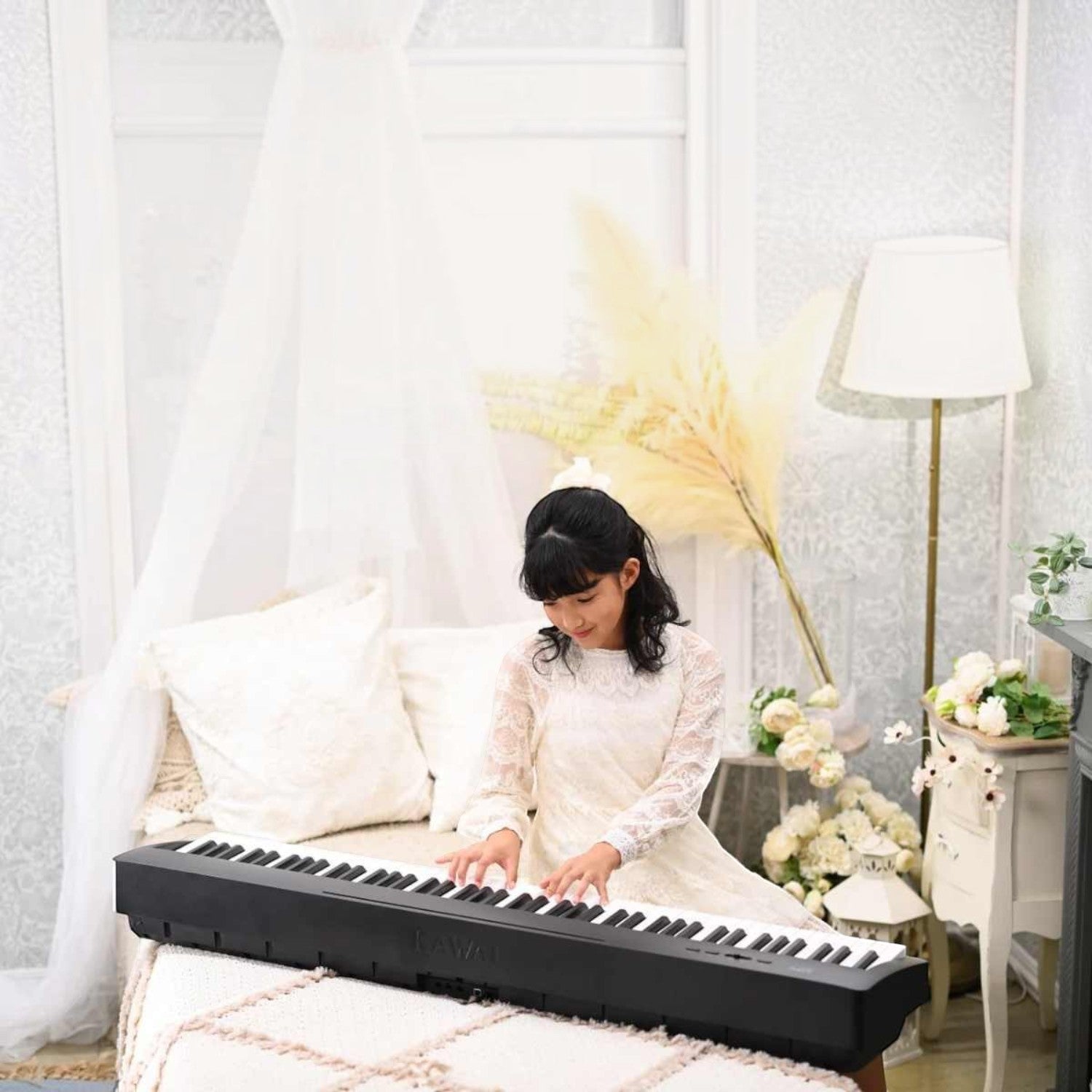 Cô gái mặc váy trắng chơi đàn piano điện Kawai ES60 màu đen tại TÂN NHẠC CỤ trong không gian phòng ngủ ấm áp