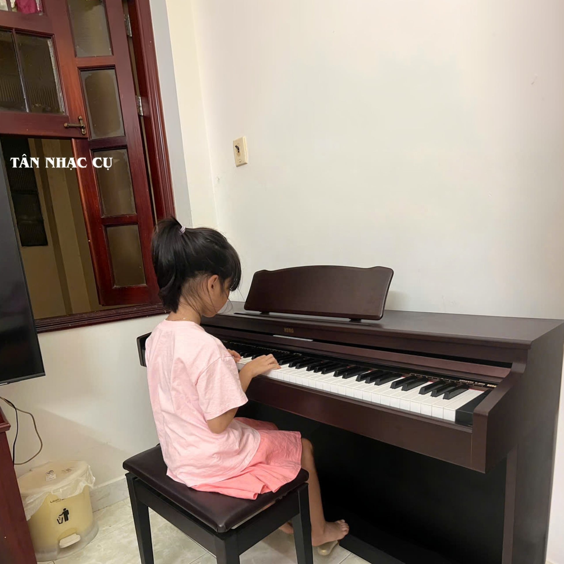 Bé gái đang chơi đàn piano điện Korg C3000 màu nâu gỗ sang trọng tại TÂN NHẠC CỤ