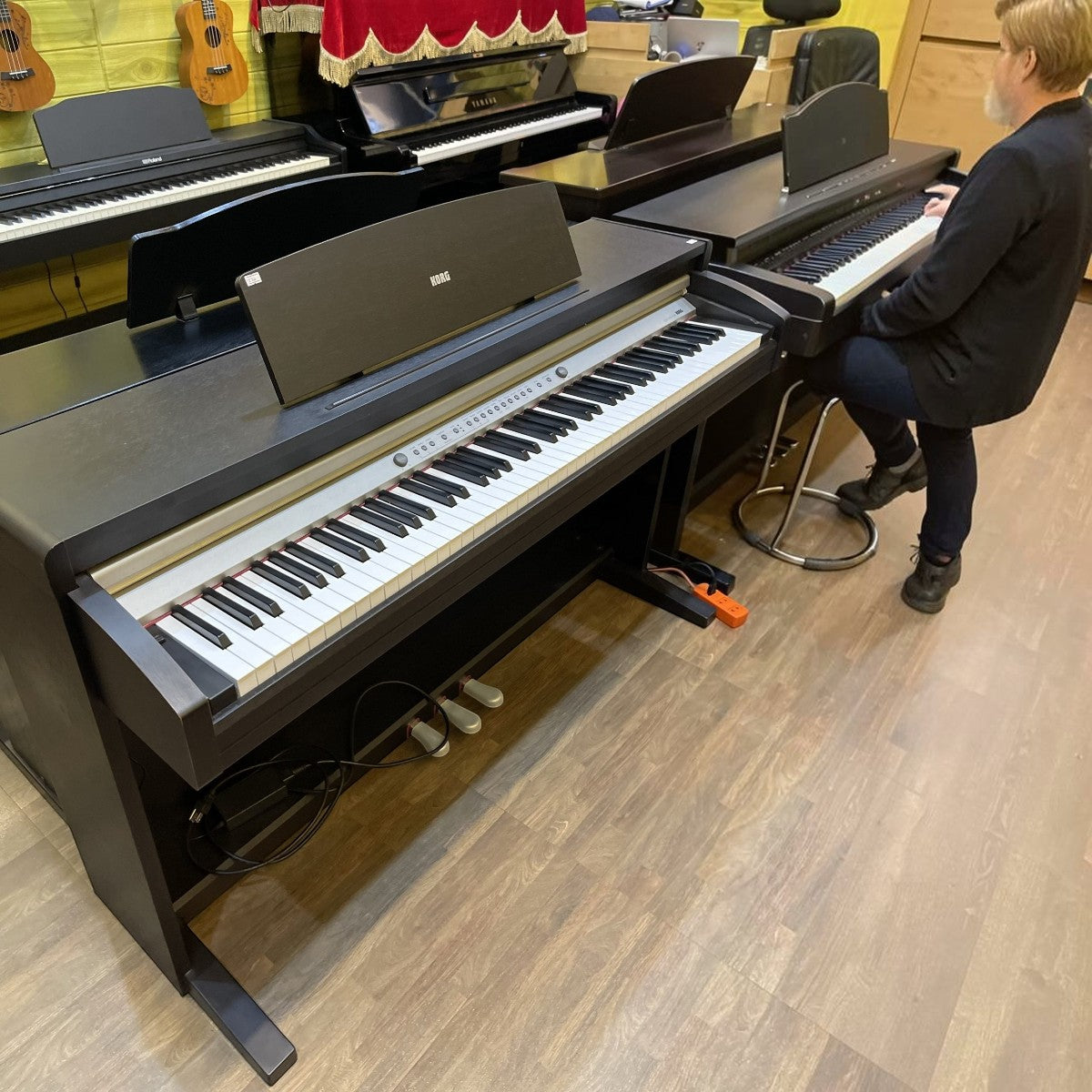 Đàn piano điện Korg C320 màu đen dáng tủ tại cửa hàng TÂN NHẠC CỤ với người đang thử phím RH3