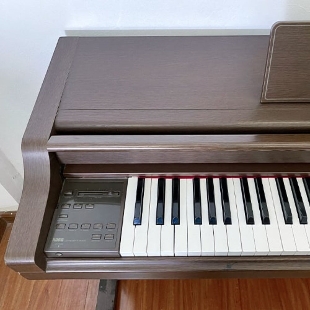 Đàn piano điện TÂN NHẠC CỤ Korg C6000 dáng tủ màu nâu gỗ với bàn phím búa 88 phím và bảng điều khiển bên trái