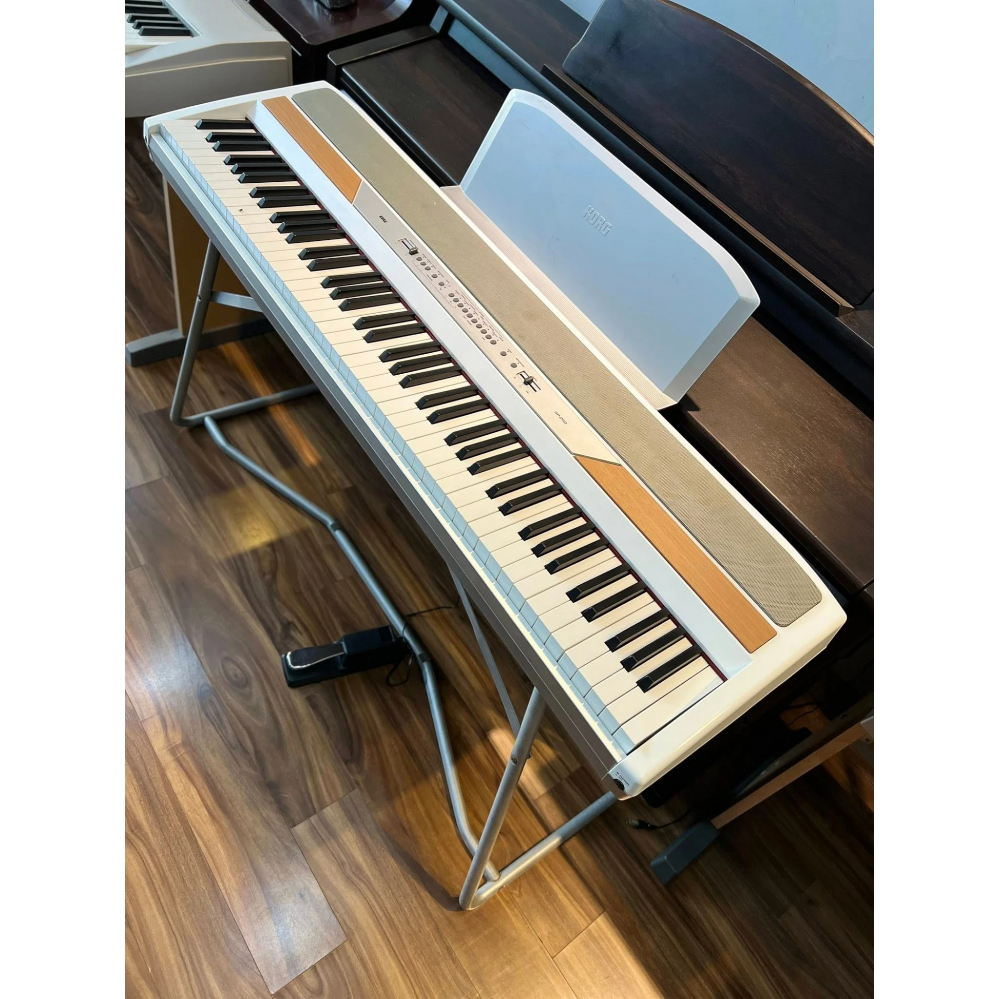 Đàn piano điện Korg SP-250 màu trắng tại TÂN NHẠC CỤ, kèm chân đứng và pedal, thiết kế gọn gàng.