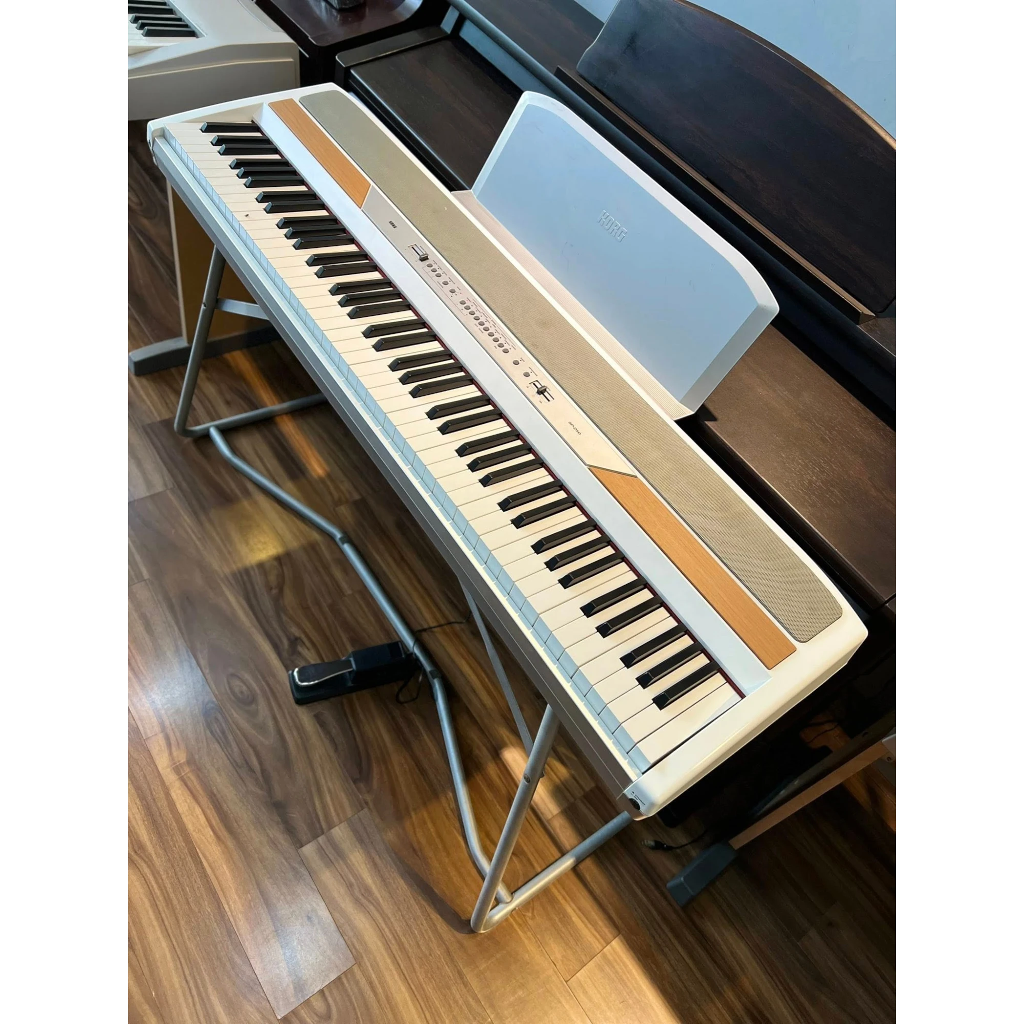 Đàn piano điện Korg SP-250 màu trắng tại TÂN NHẠC CỤ, kèm chân đứng và pedal, thiết kế gọn gàng.