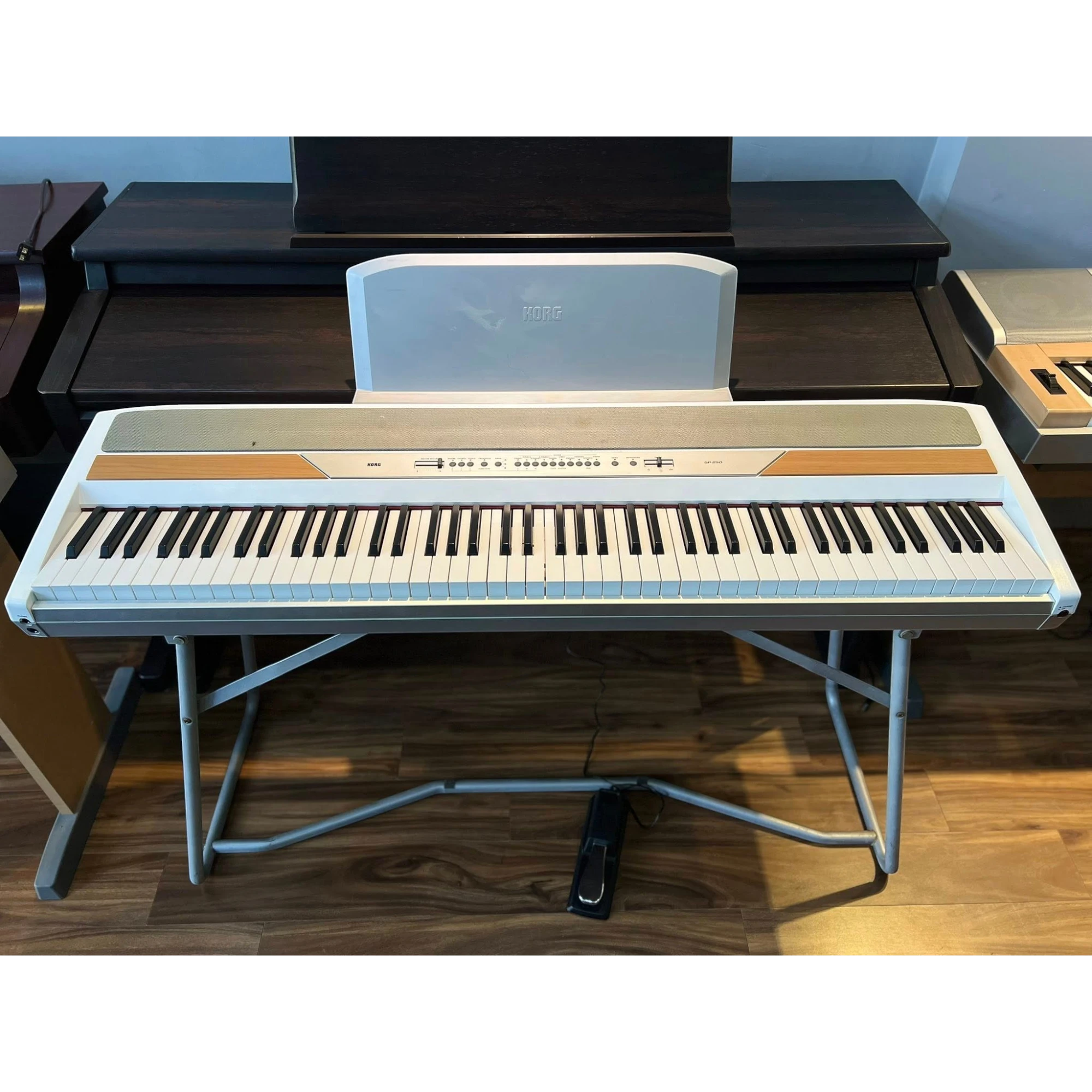 Đàn piano điện Korg SP-250 màu trắng tại cửa hàng TÂN NHẠC CỤ, thiết kế gọn kèm chân đứng và pedal.