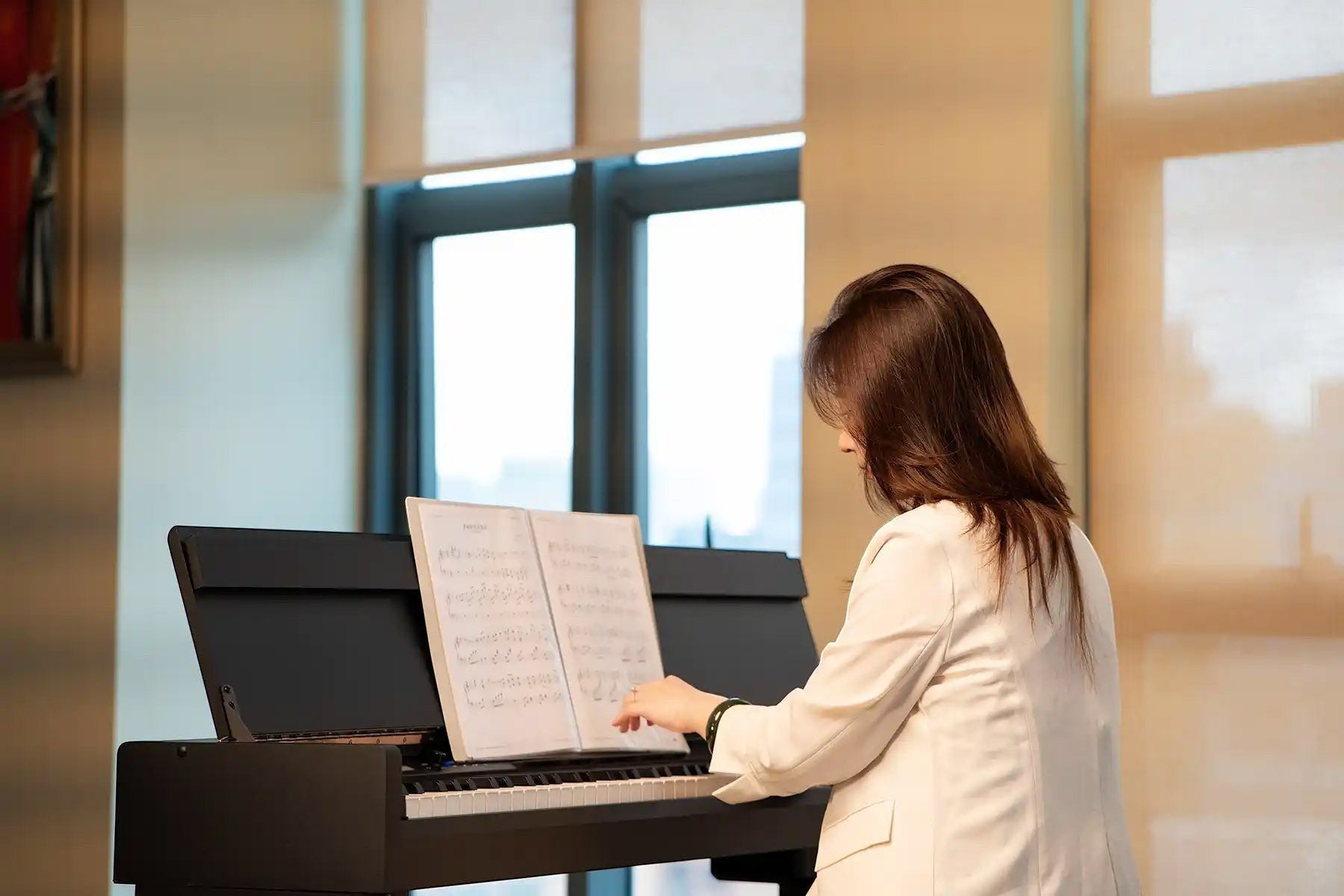 Người phụ nữ chơi đàn piano điện NUX NCK330 dáng tủ màu đen tại Tân Nhạc Cụ