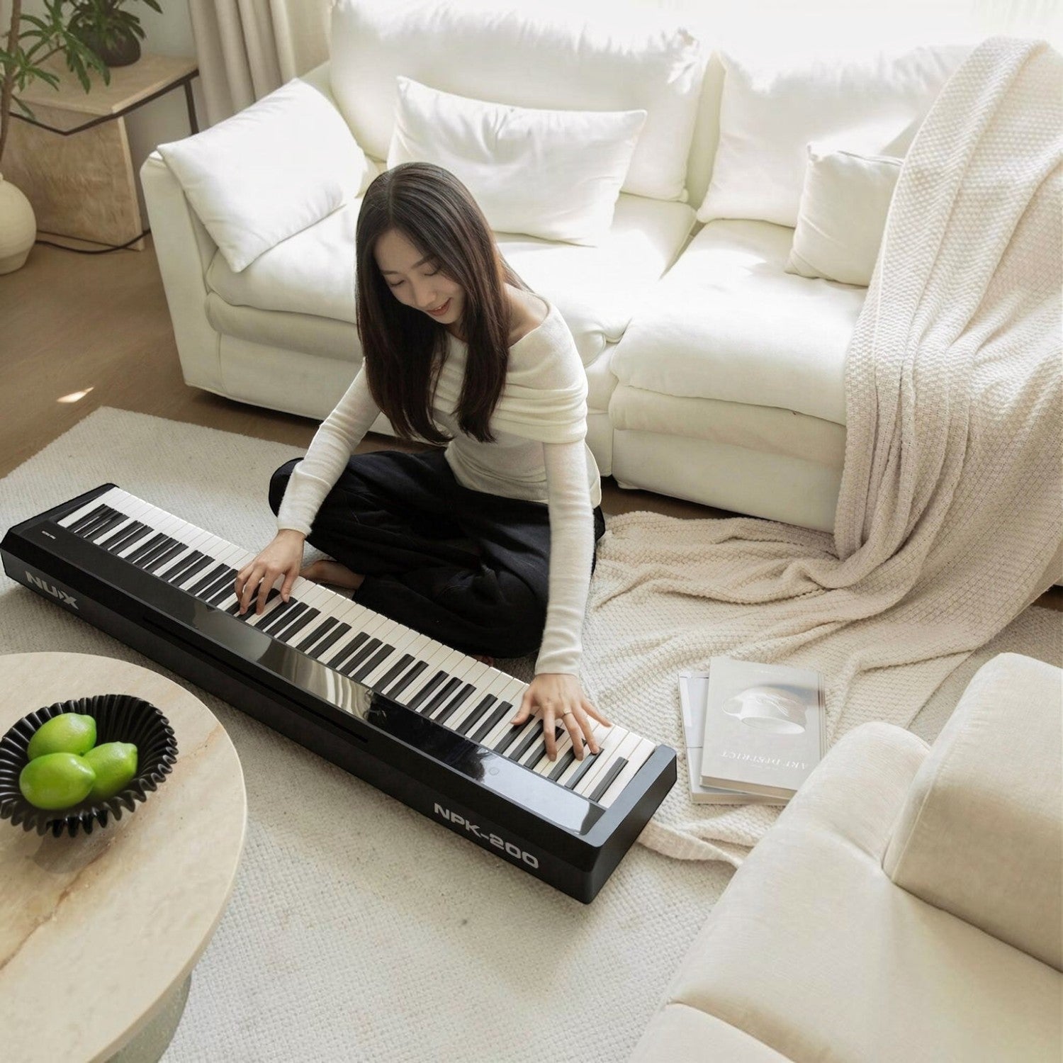 Cô gái chơi đàn piano điện Nux NPK200 màu đen hiện đại trong không gian phòng khách ấm cúng tại TÂN NHẠC CỤ