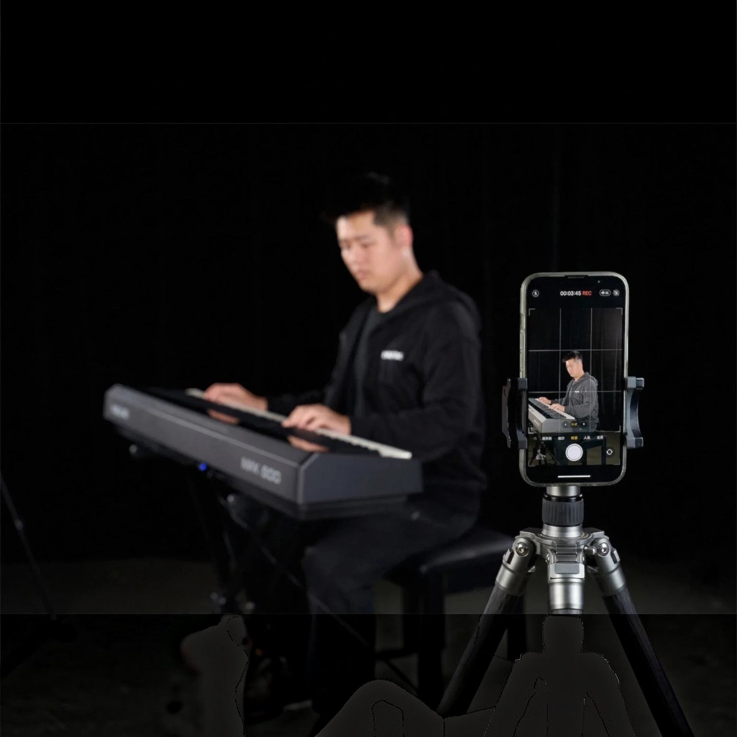 Nam nhạc sĩ đang chơi đàn piano điện Nux NPK200 màu đen, được quay phim bằng điện thoại trên chân máy tại TÂN NHẠC CỤ